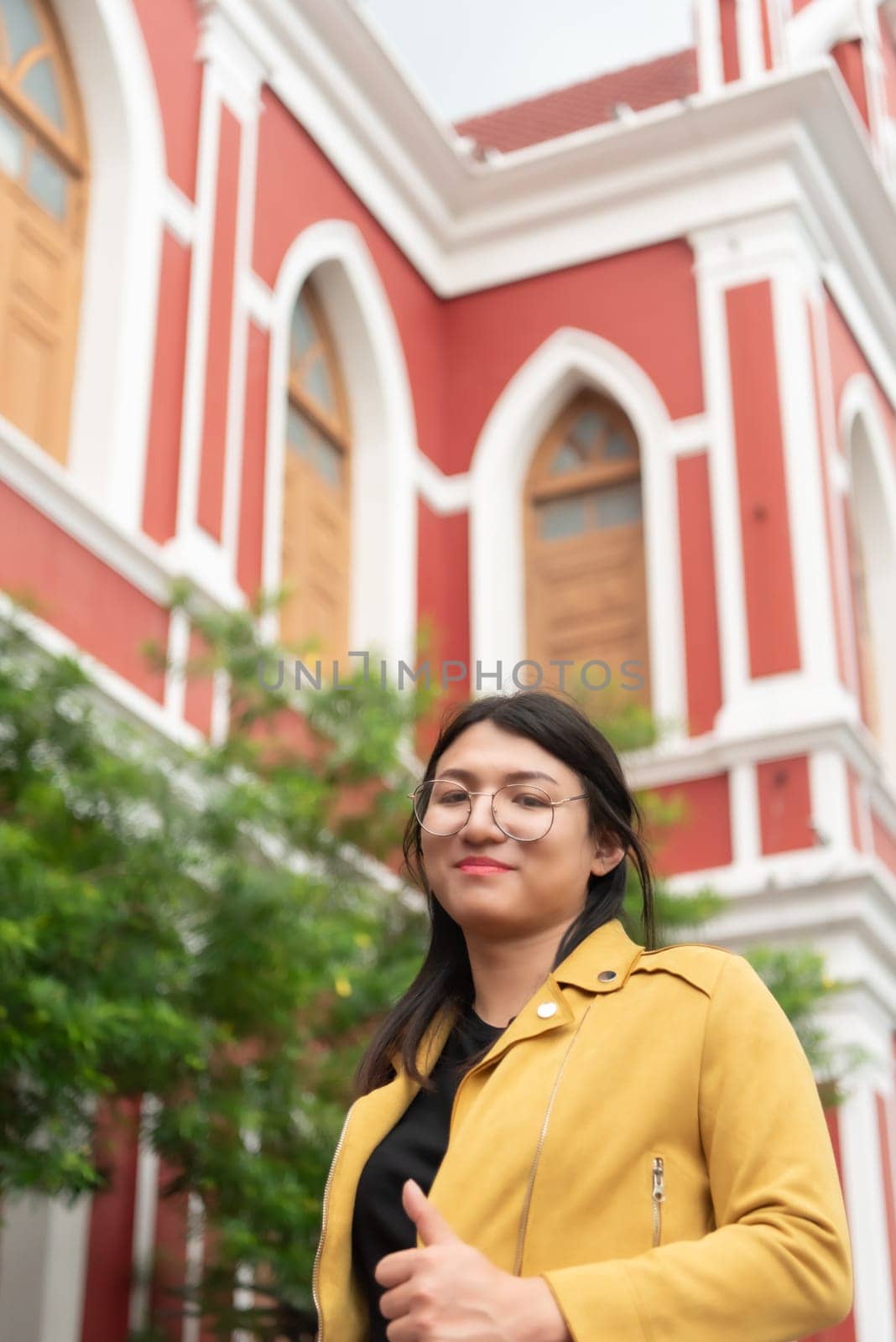 Beautiful asian woman (LGBTQ) natural makeup wear fashion yellow leather clothes with glasses posing at old town and vintage building outdoor fashion style