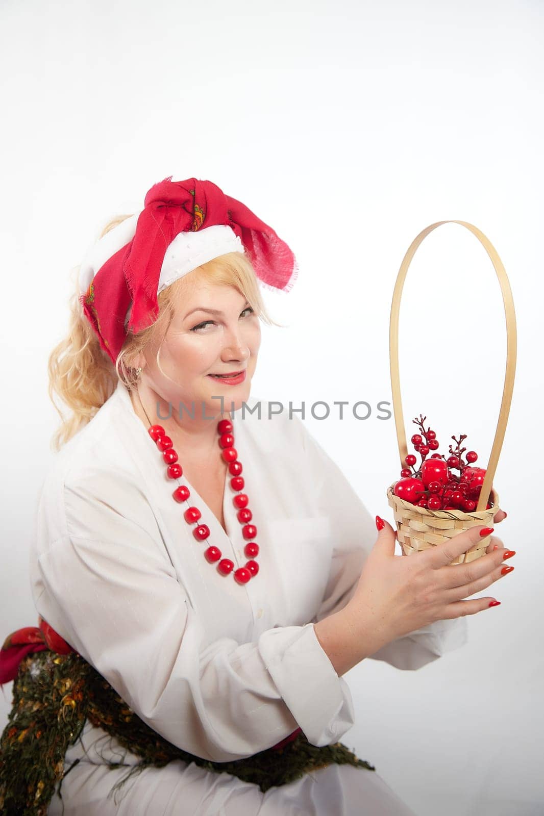 Portrait of heerful funny adult mature woman solokha with red berries. Female model in national ethnic Slavic style. Stylized Ukrainian, Belarusian or Russian woman in comic photo shoot