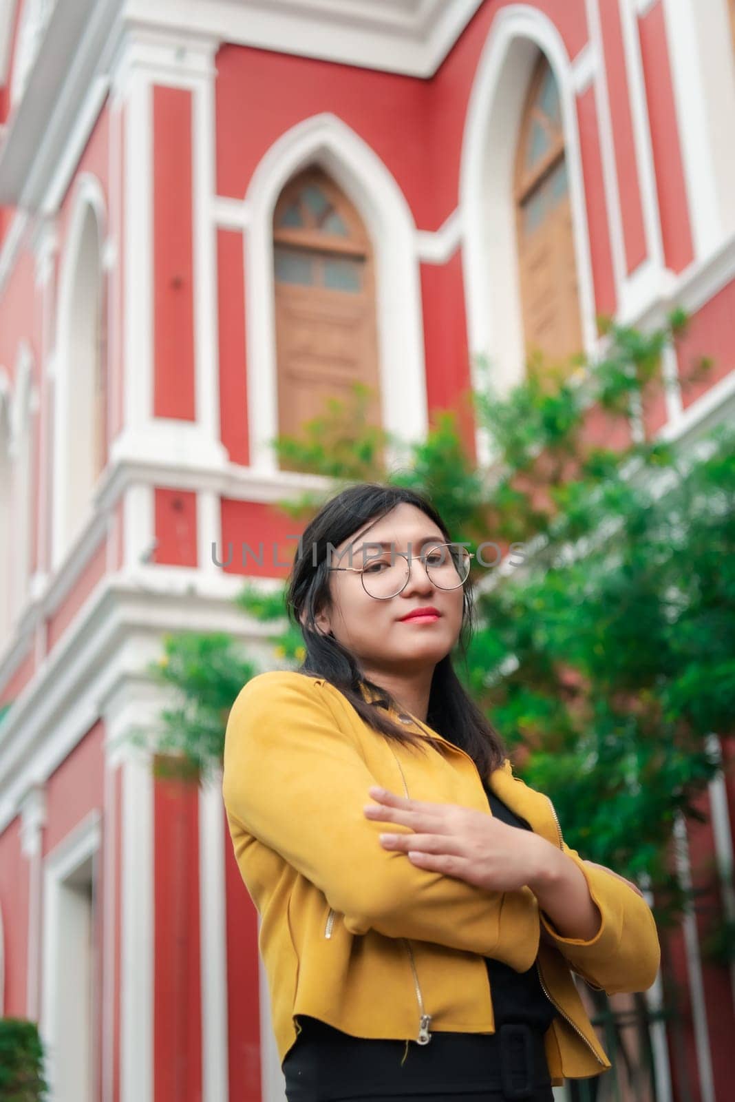 Beautiful asian woman (LGBTQ) natural makeup wear fashion yellow leather clothes with glasses posing at old town and vintage building outdoor fashion style