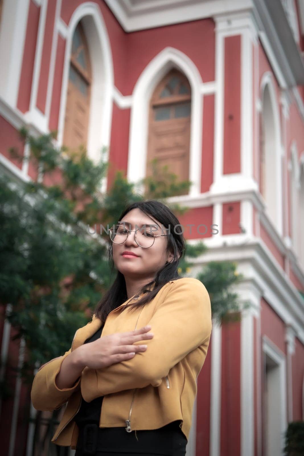 Beautiful asian woman (LGBTQ) natural makeup wear fashion yellow leather clothes with glasses posing at old town and vintage building outdoor fashion style