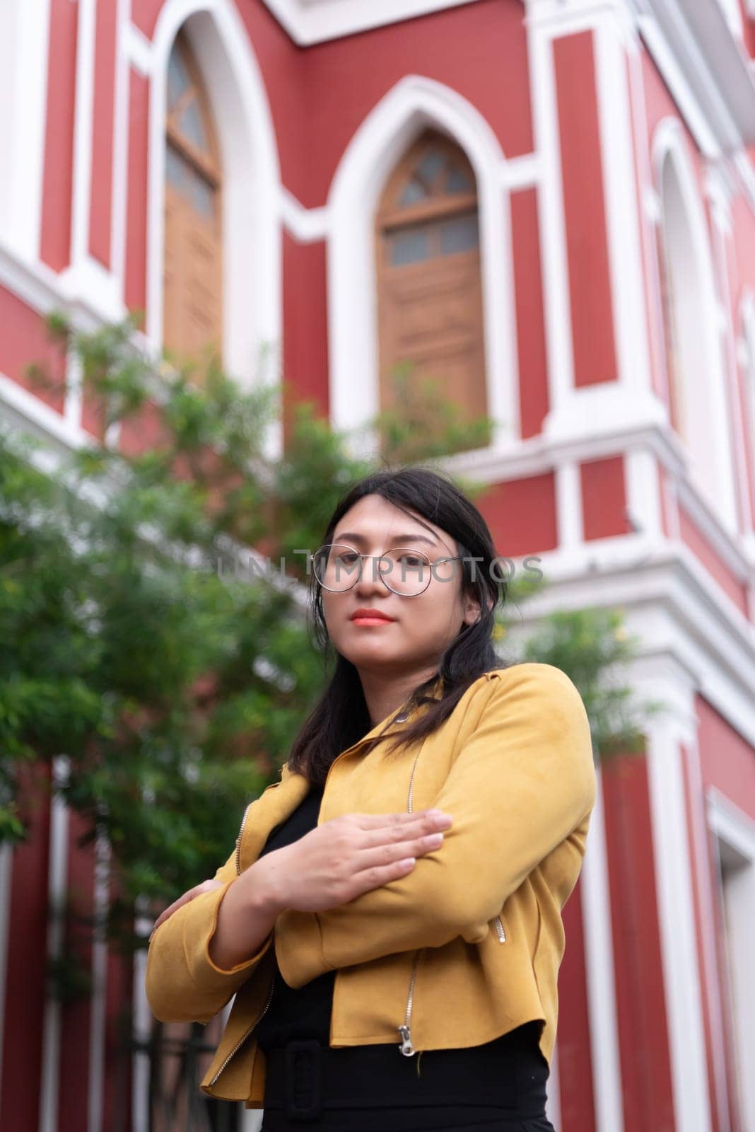 Beautiful asian woman (LGBTQ) natural makeup wear fashion yellow leather clothes with glasses posing at old town and vintage building outdoor fashion style