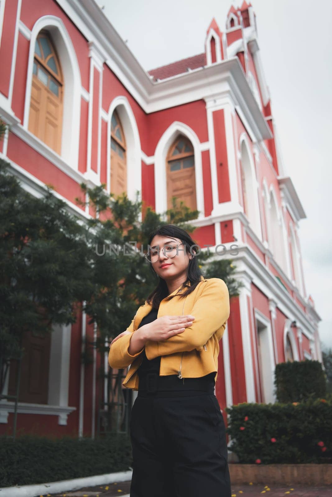 Beautiful asian woman (LGBTQ) natural makeup wear fashion yellow leather clothes with glasses posing at old town and vintage building outdoor fashion style