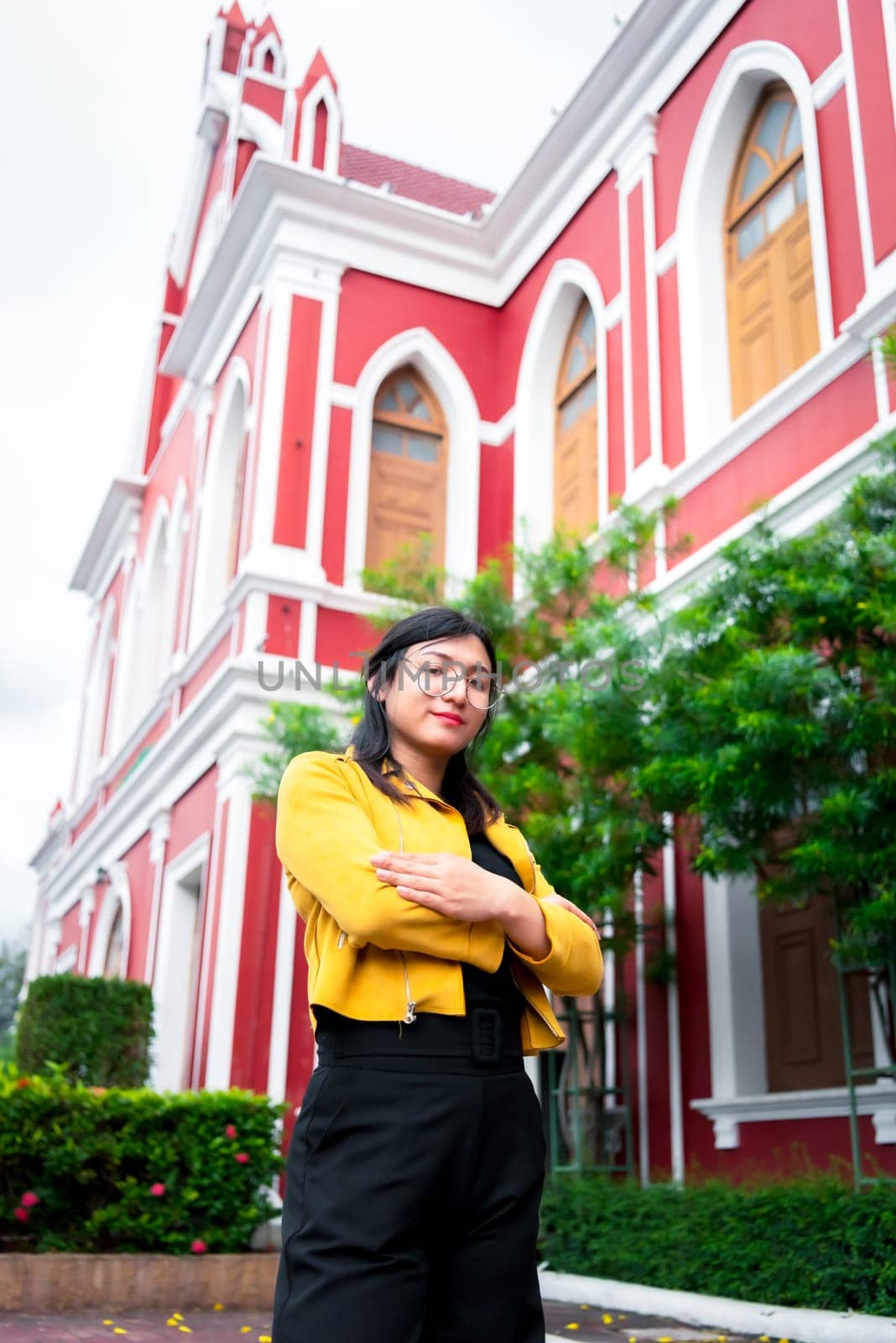 Beautiful asian woman (LGBTQ) natural makeup wear fashion yellow leather clothes with glasses posing at old town and vintage building outdoor fashion style