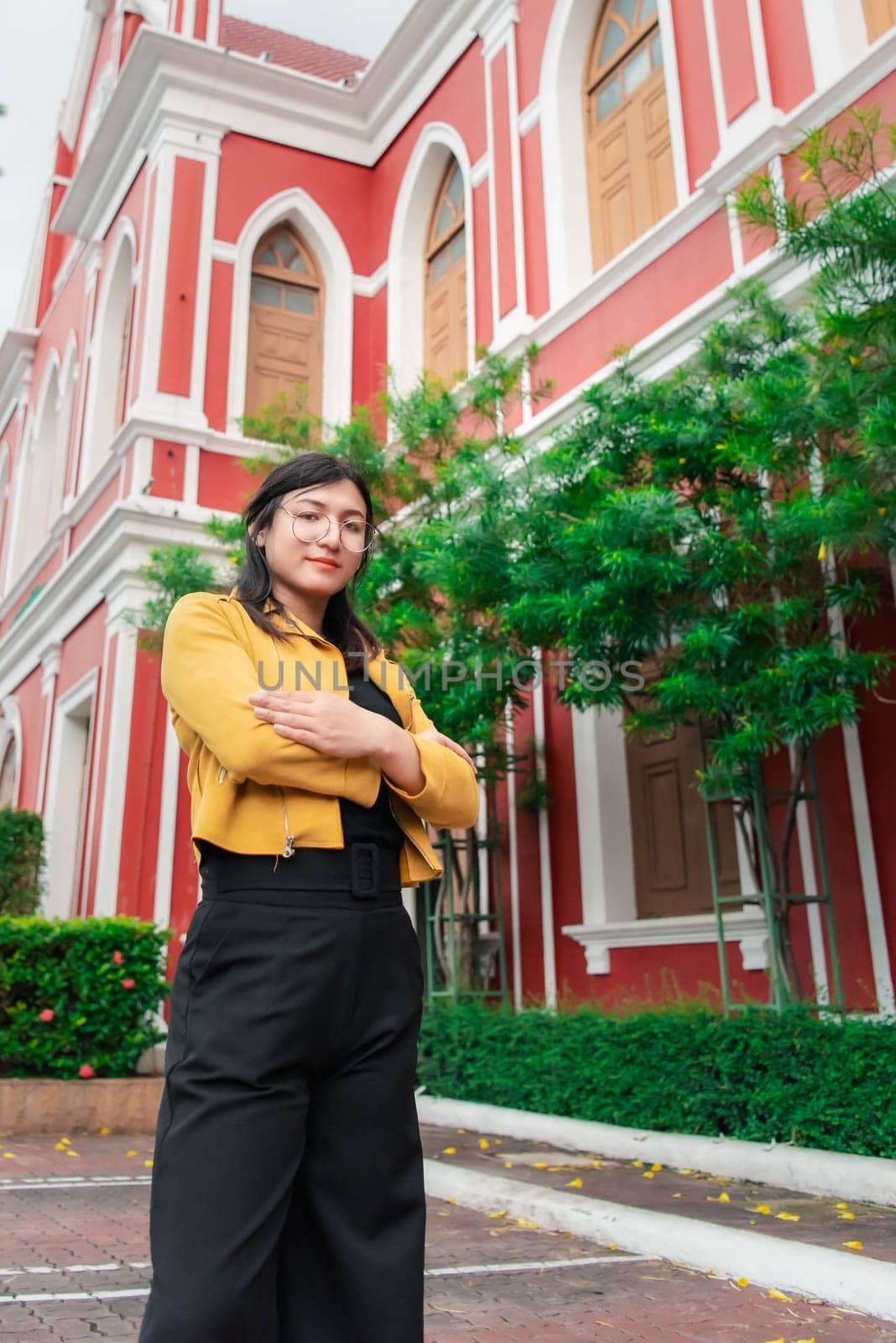 Beautiful asian woman (LGBTQ) natural makeup wear fashion yellow leather clothes with glasses posing at old town and vintage building outdoor fashion style