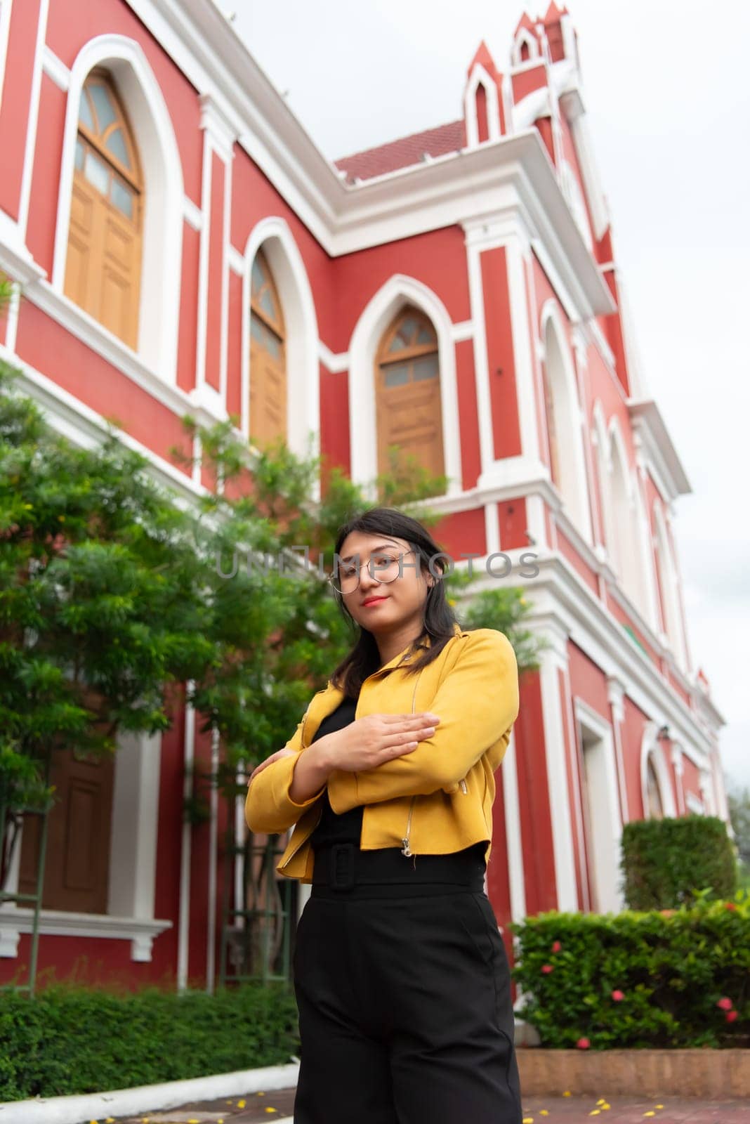 Beautiful asian woman (LGBTQ) natural makeup wear fashion yellow leather clothes with glasses posing at old town and vintage building outdoor fashion style