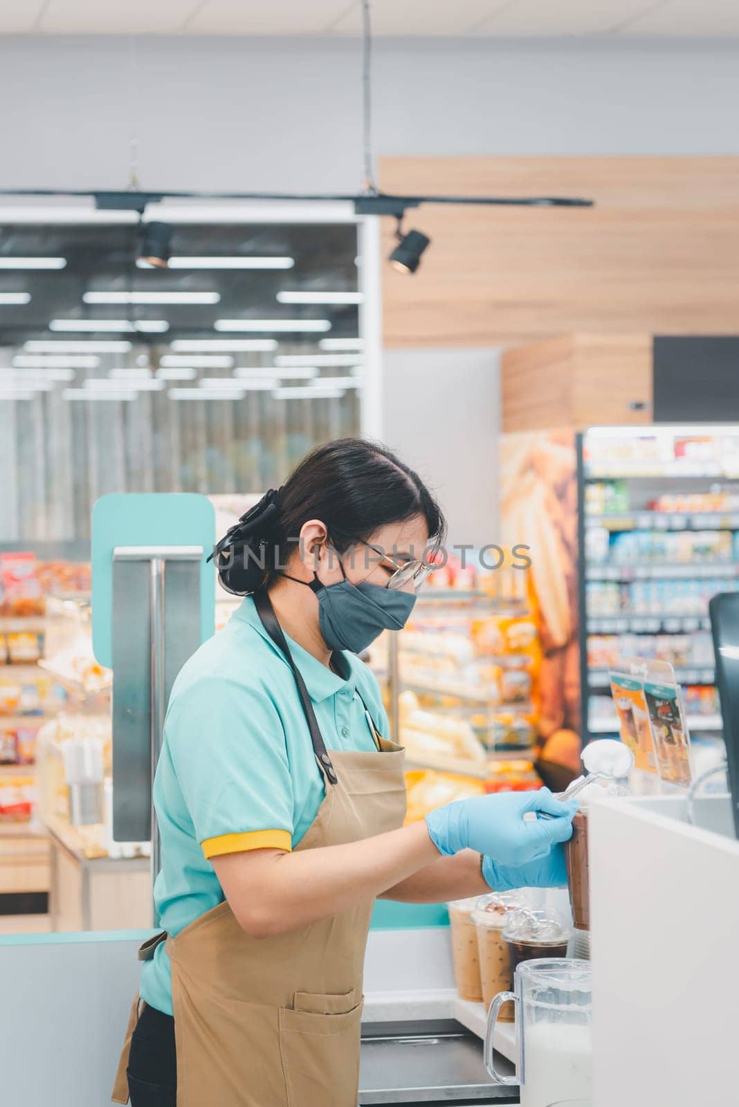 Asian woman barista pouring latte in coffee shop by NongEngEng