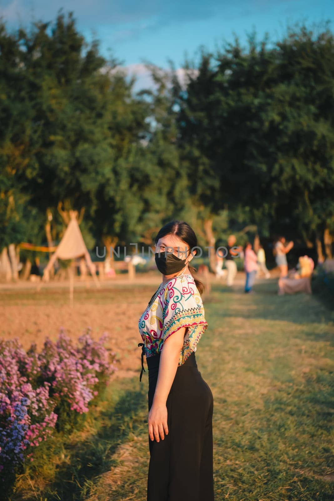 Beautiful asian woman (LGBTQ) natural makeup wear fashion relax clothes posing at nature of flower park or flower garden field lush growing for travel popular landmark in asia outdoor fashion style