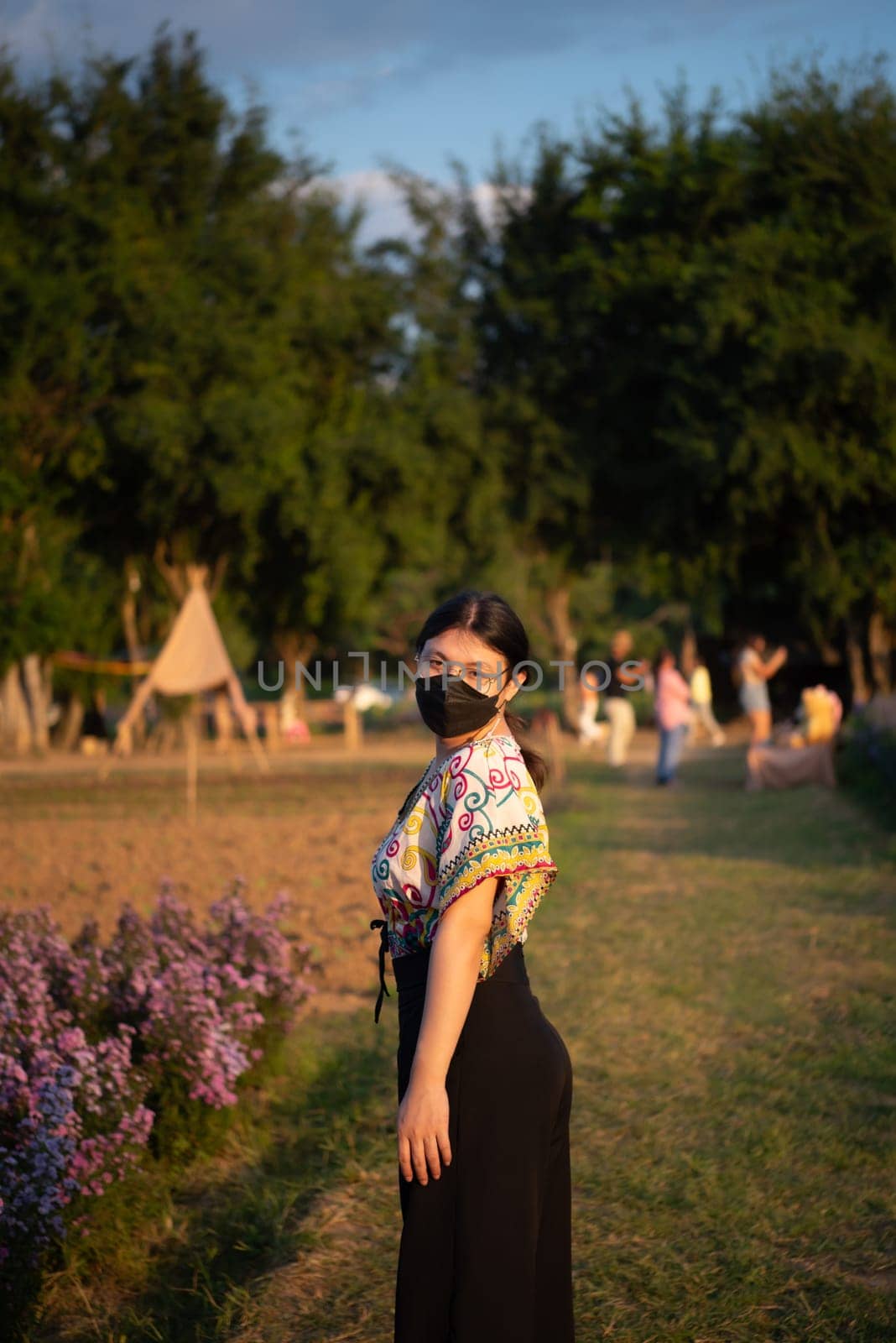 Beautiful asian woman (LGBTQ) natural makeup wear fashion relax clothes posing at nature of flower park or flower garden field lush growing for travel popular landmark in asia outdoor fashion style