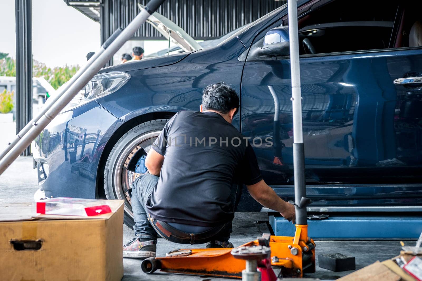 Car mechanic or serviceman disassembly and checking a disc brake and asbestos brake pads for fix and repair problem at car garage or repair shop