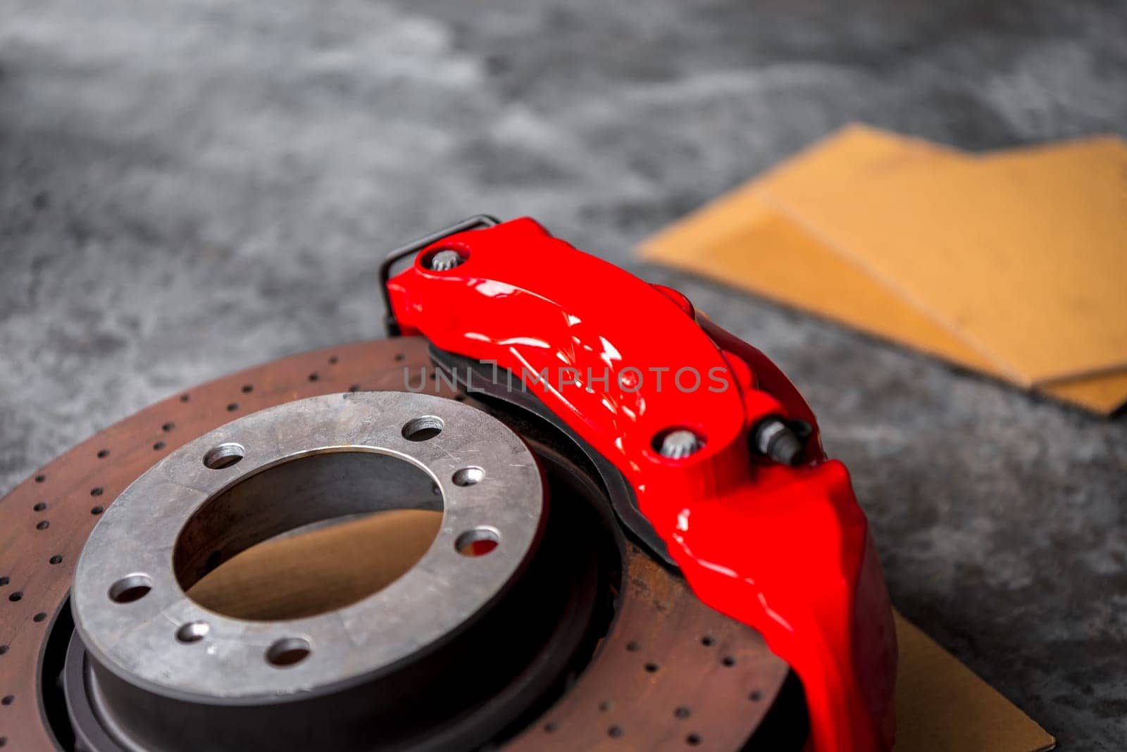 Car mechanic or serviceman disassembly and checking a disc brake and asbestos brake pads for fix and repair problem at car garage or repair shop