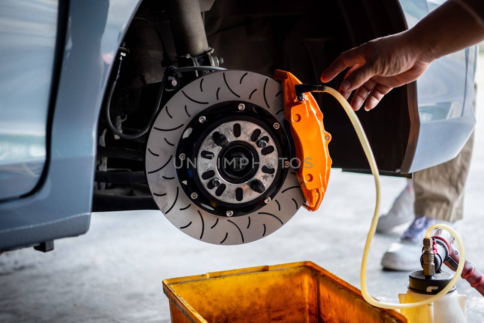 Car mechanic or serviceman disassembly and checking a disc brake and asbestos brake pads for fix and repair problem at car garage or repair shop