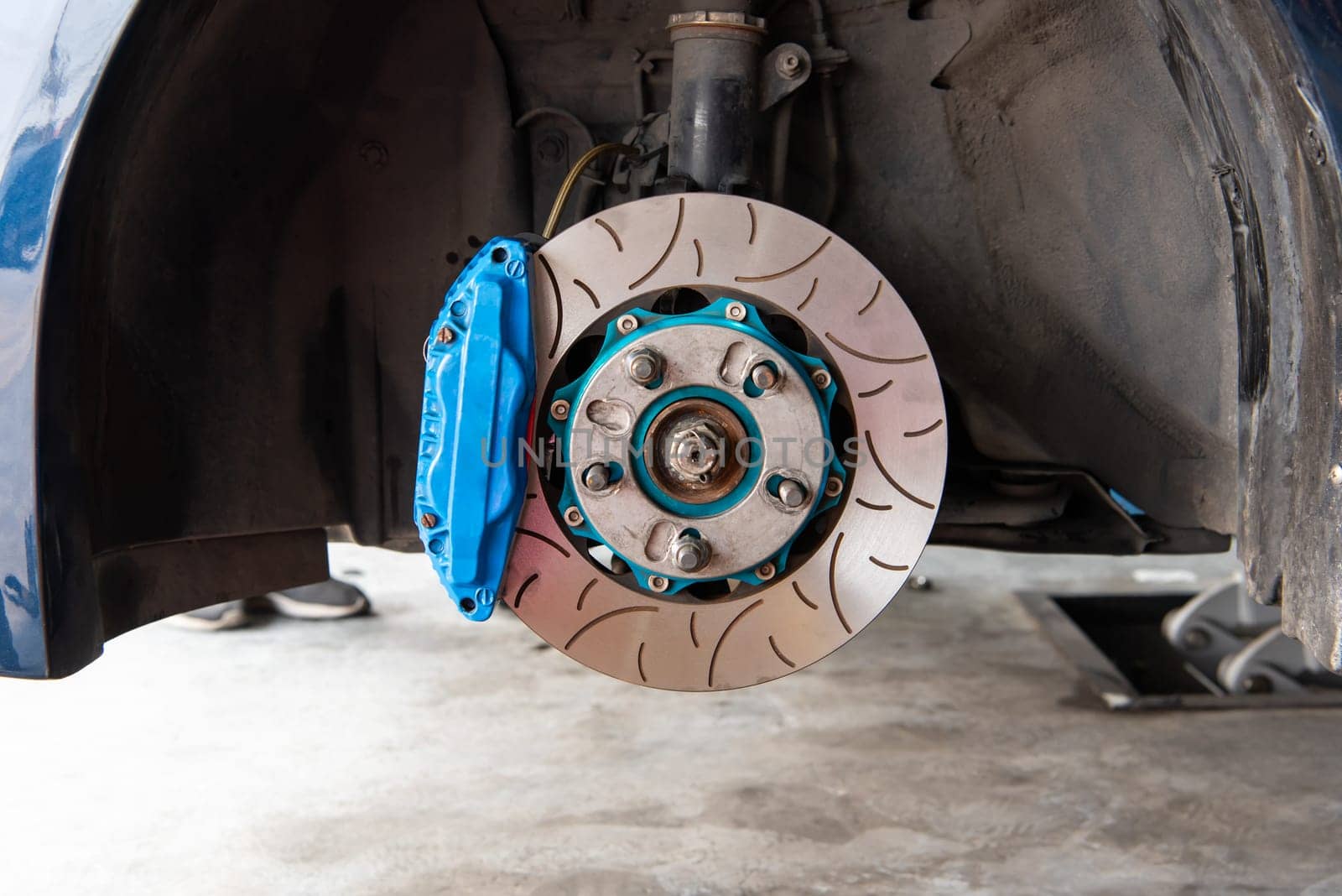 Car mechanic or serviceman disassembly and checking a disc brake and asbestos brake pads for fix and repair problem at car garage or repair shop