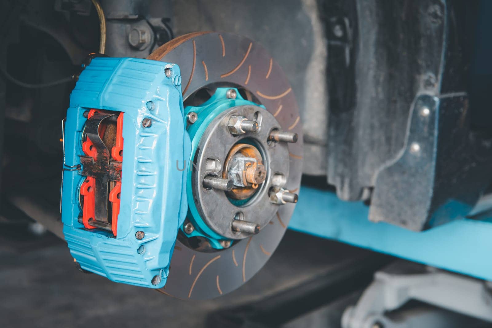 Car mechanic or serviceman disassembly and checking a disc brake and asbestos brake pads for fix and repair problem at car garage or repair shop