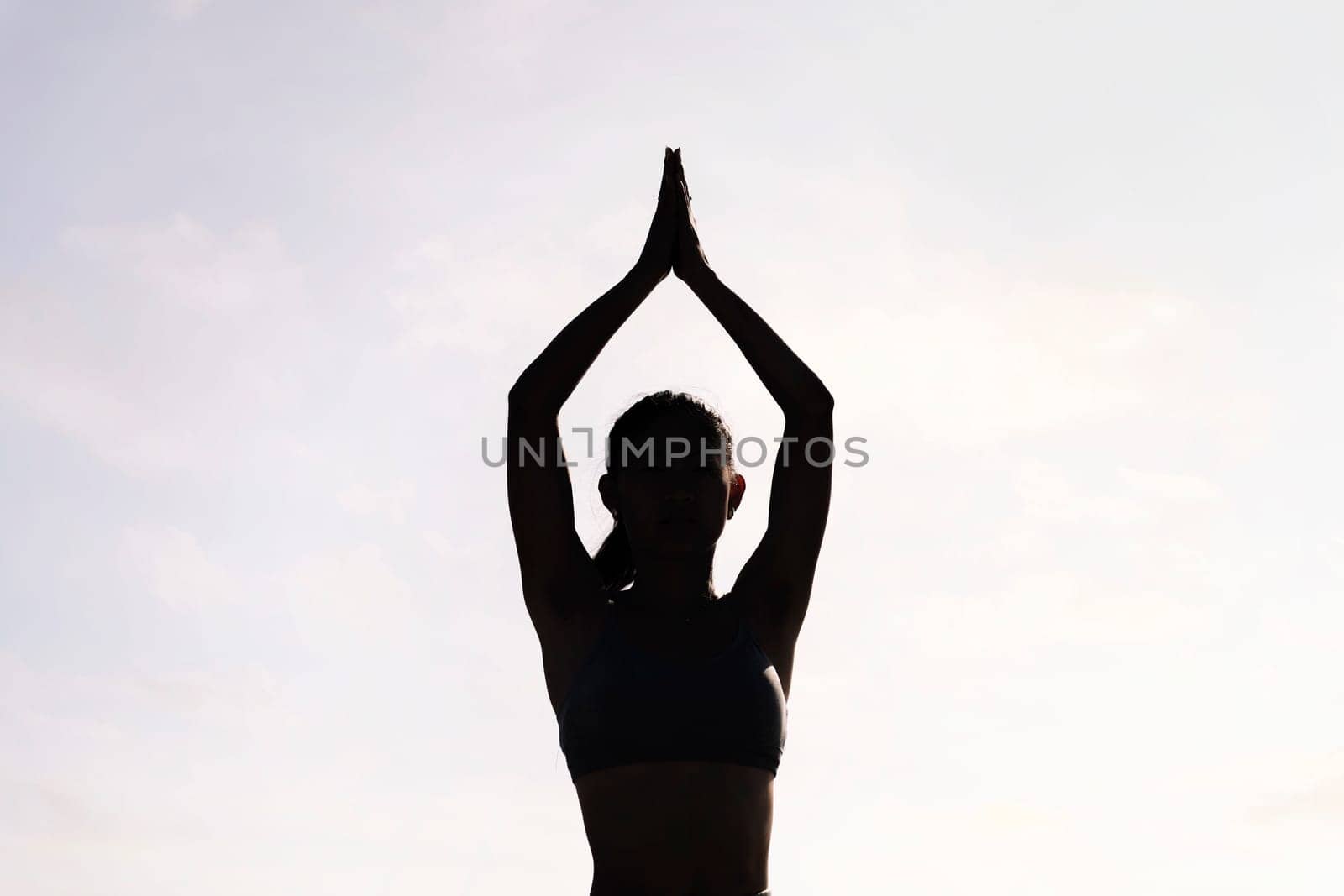 backlight of young woman doing yoga meditation, concept of mental relaxation and healthy lifestyle