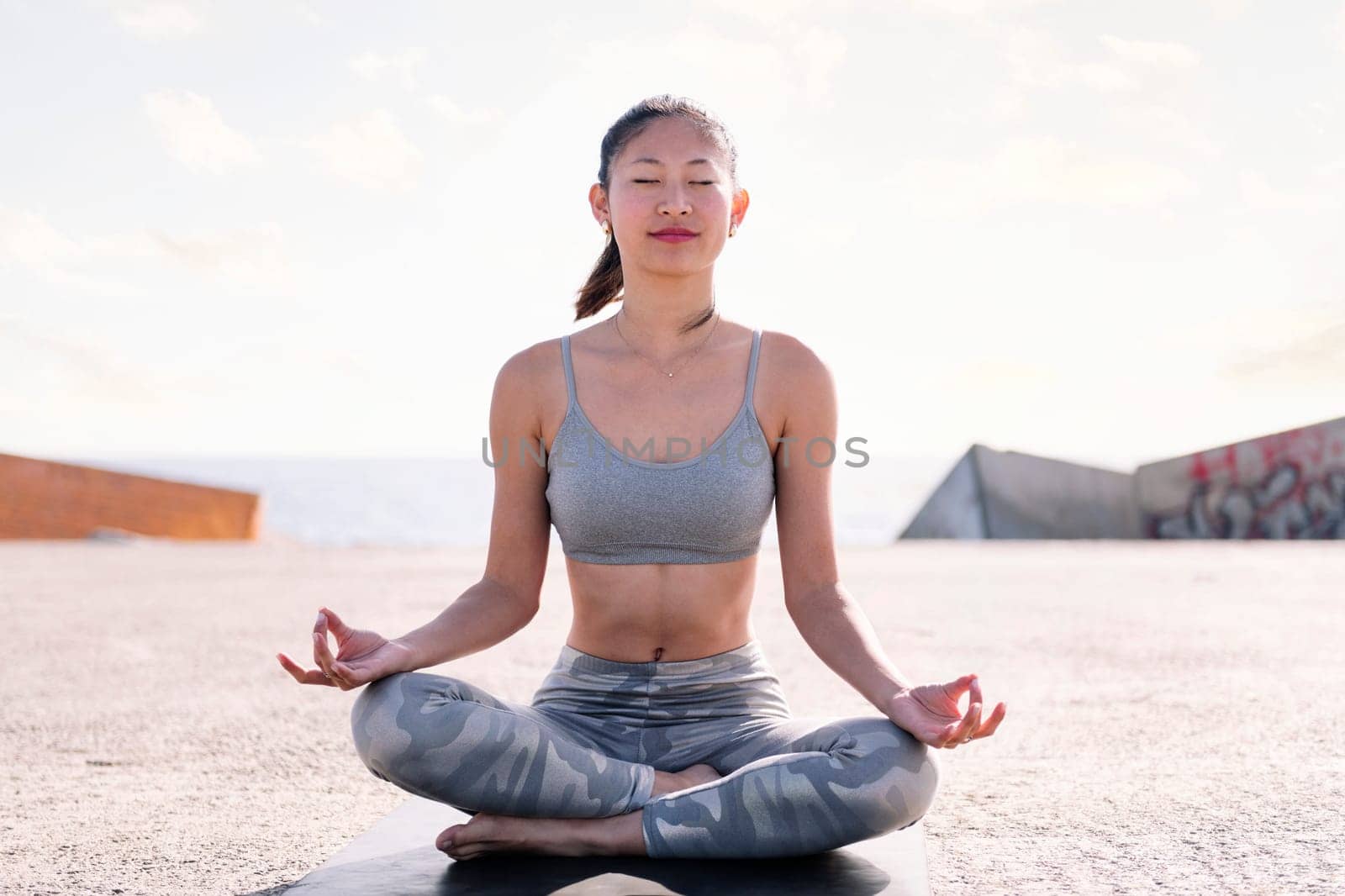 woman doing yoga meditation sitting by the sea by raulmelldo