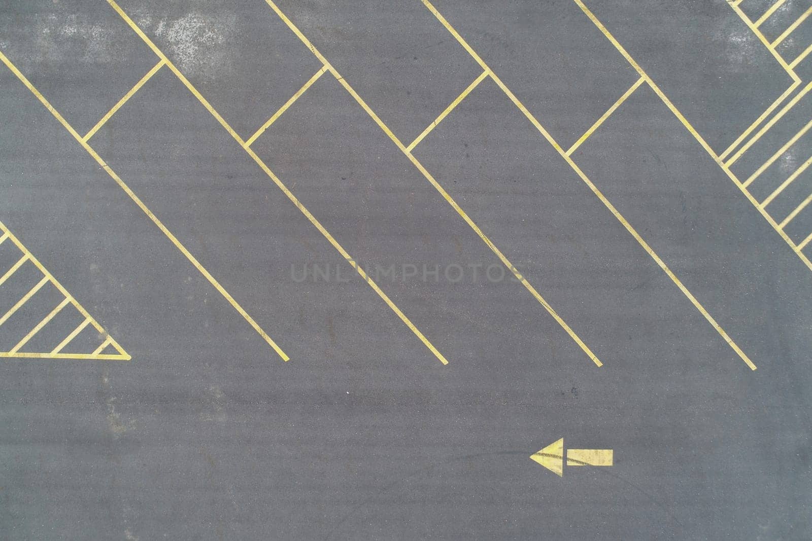 angled asphalt parking lot with yellow lines an left pointing arrow to direct traffic