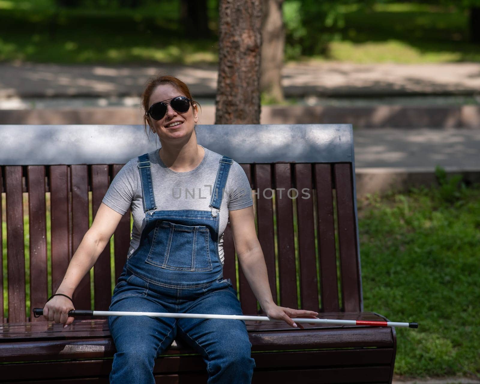 Blind red-haired pregnant woman sitting on a bench outdoors. by mrwed54