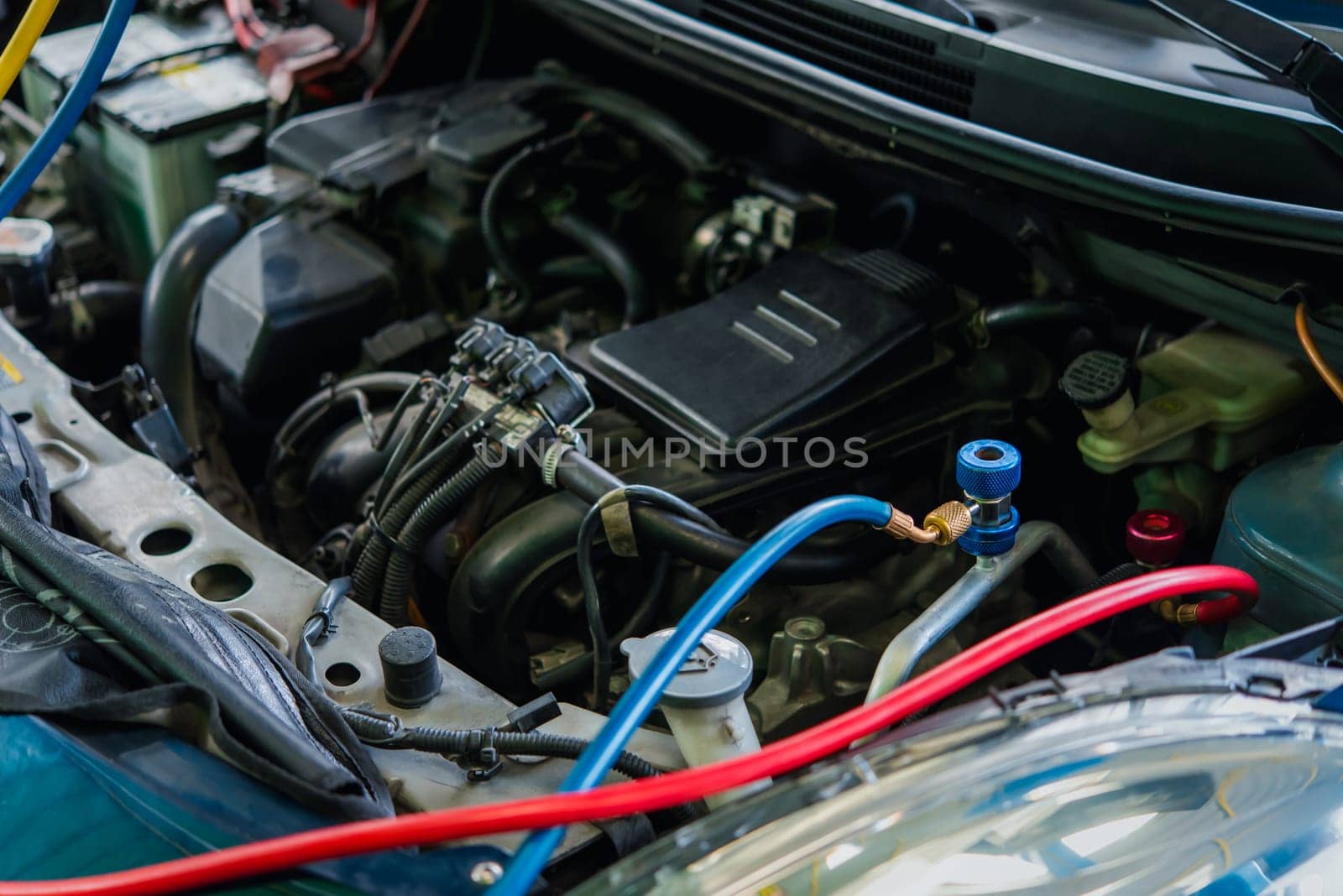 Car mechanic or serviceman refilling air condition and checking a air compressor for fix and repair problem at car garage or repair shop