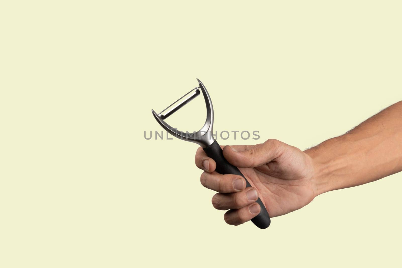 Black male hand holding a potato peeler isolated on green background by TropicalNinjaStudio