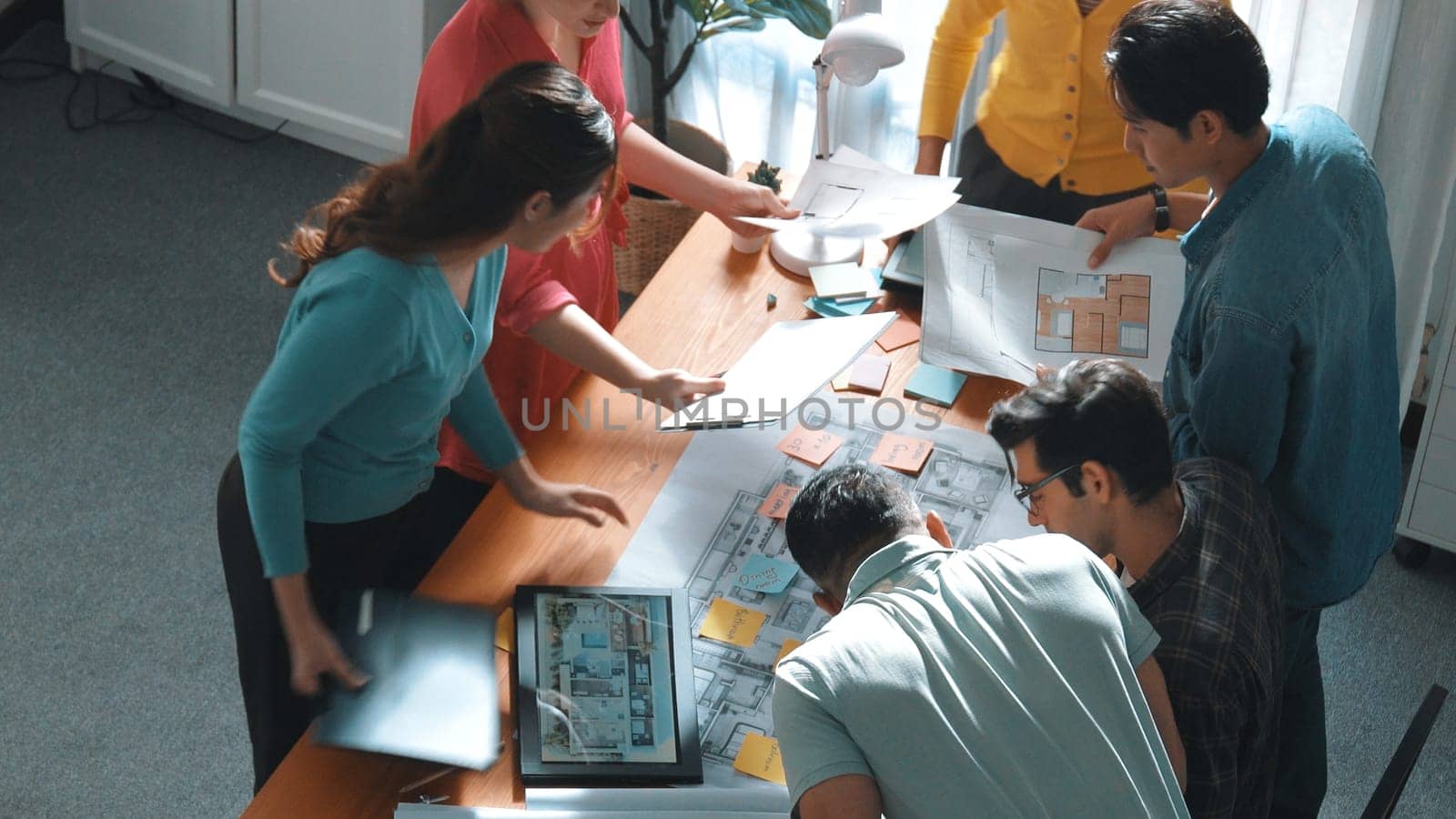 Top view of civil engineer writing and planning by using sticky notes to brainstorm idea. Top down aerial view of business people taking a note at table with project plans and equipments. Symposium.