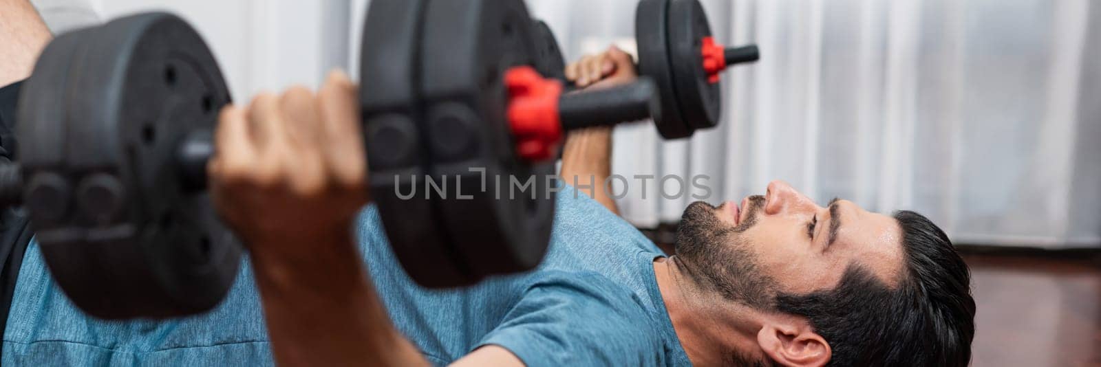 Athletic body and active sporty man lifting dumbbell at gaiety home exercise. by biancoblue