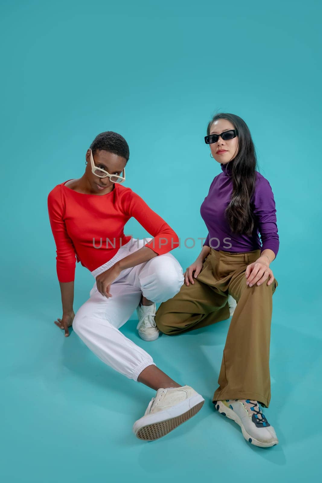 Two fashion models with sunglasses posing with attitude on a blue studio background by PaulCarr