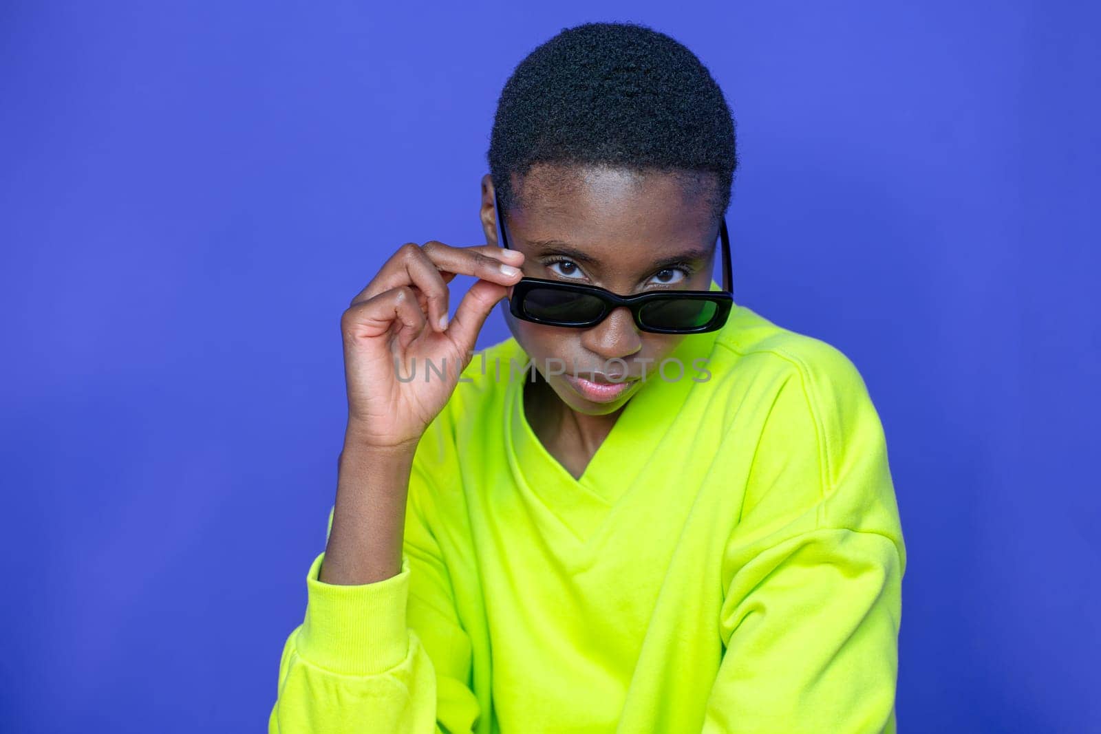 Fashion black model with sunglasses posing with attitude on blue studio background. by PaulCarr