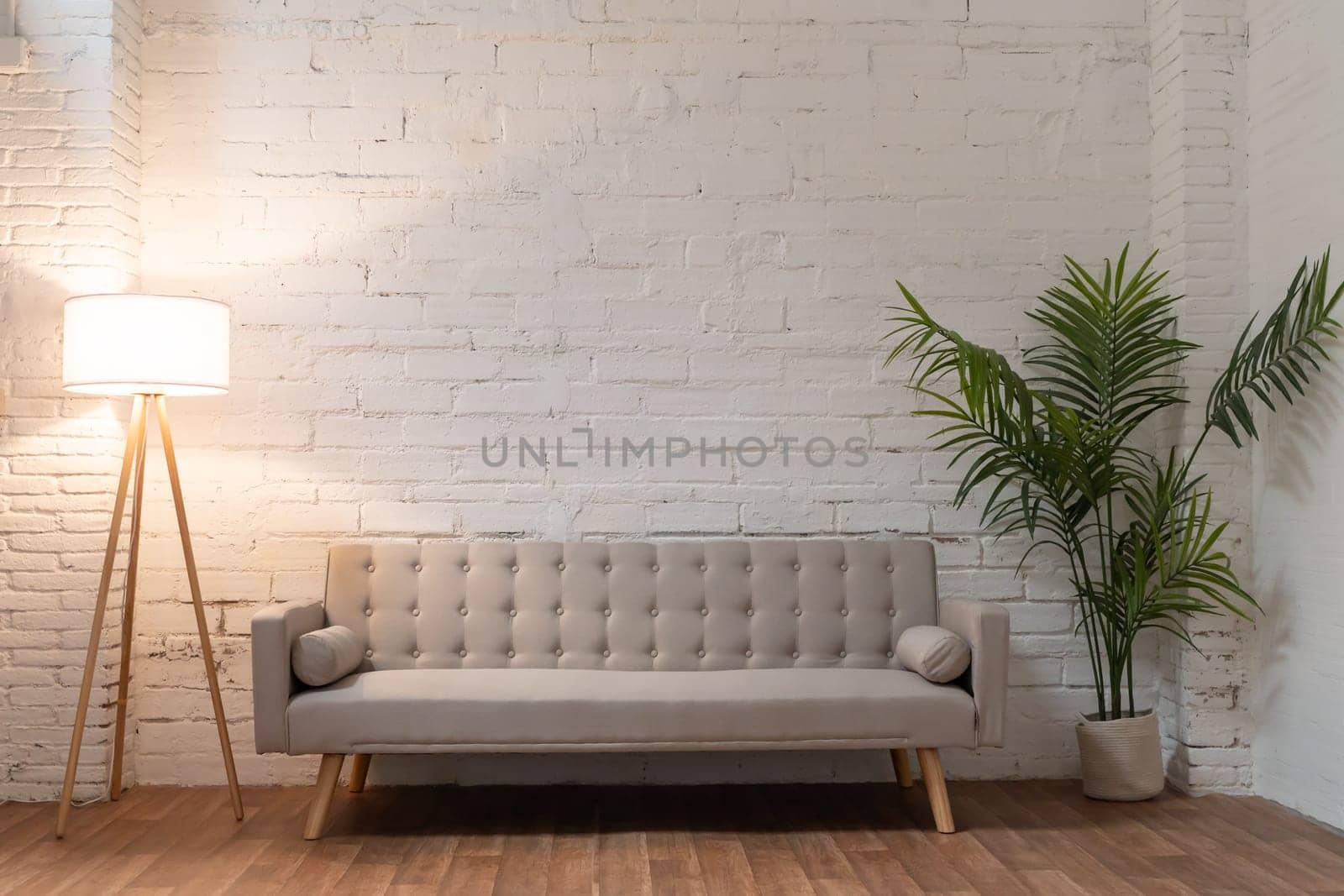 White brick wall with sofa pot with plant and light. Background photo with copy space for text. by PaulCarr