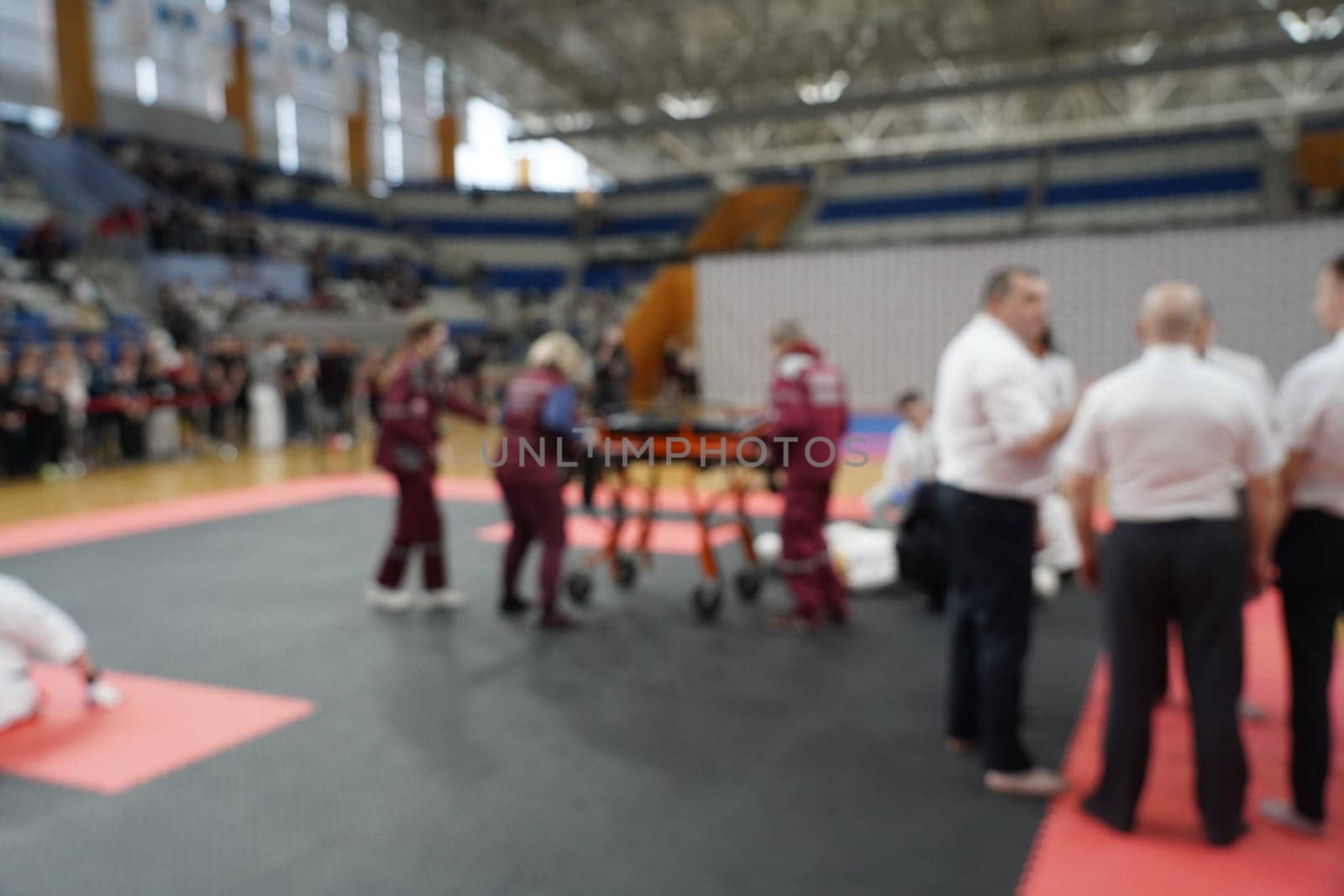 A team of doctors provides assistance to an athlete who was injured in a karate competition. Blurred background image.