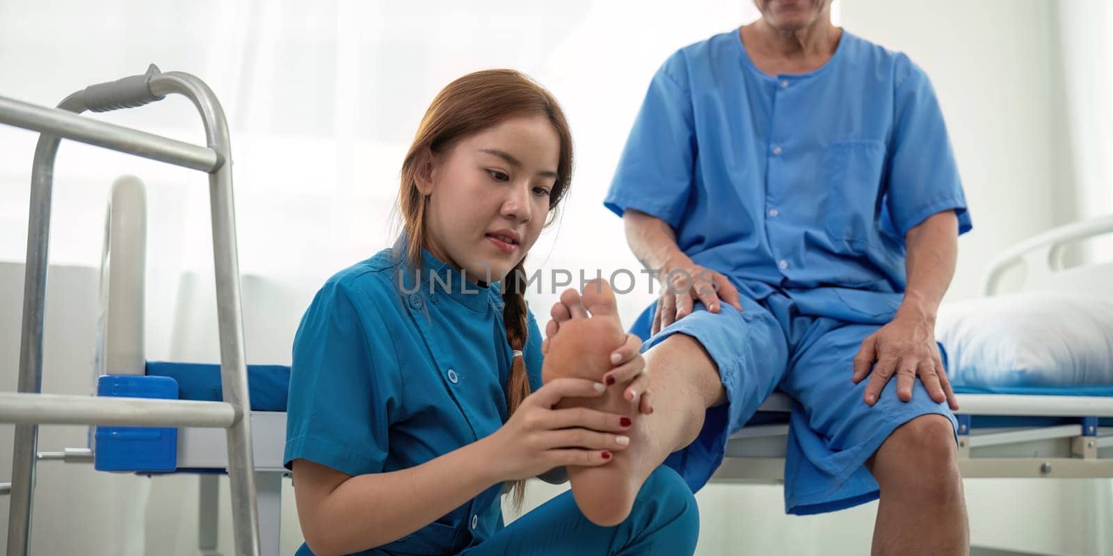 Physical therapist Asian woman, doing leg physiotherapy for elderly man to treat osteoarthritis and nerve pain in the leg to nursing at home and health care concept.