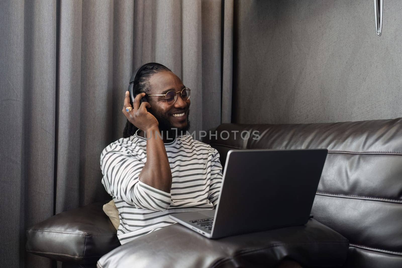 African American man relaxing on sofa and listening to music at home.