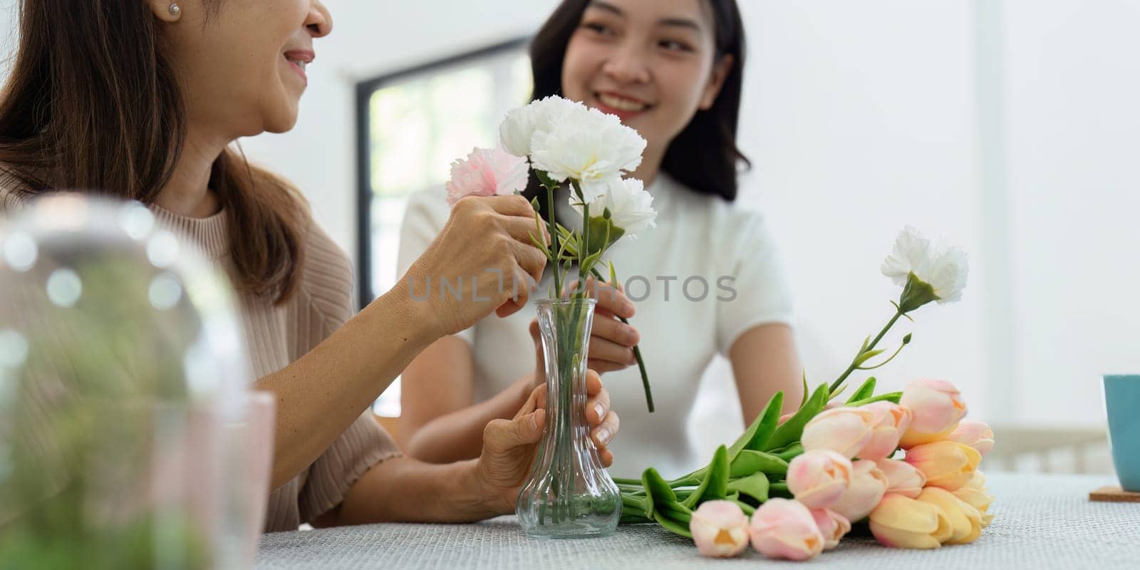 Mother and daughter arrange flower together at home on the weekend, family activities, mother and daughter do activities together on Mother's Day.