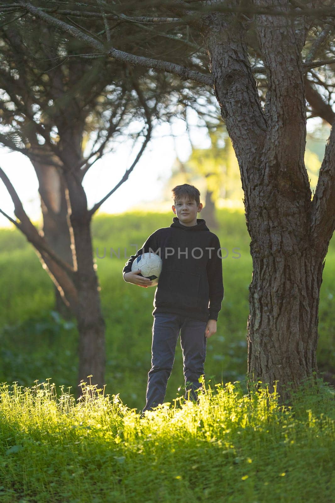 A boy is standing in a field with a soccer ball in his hand by Studia72