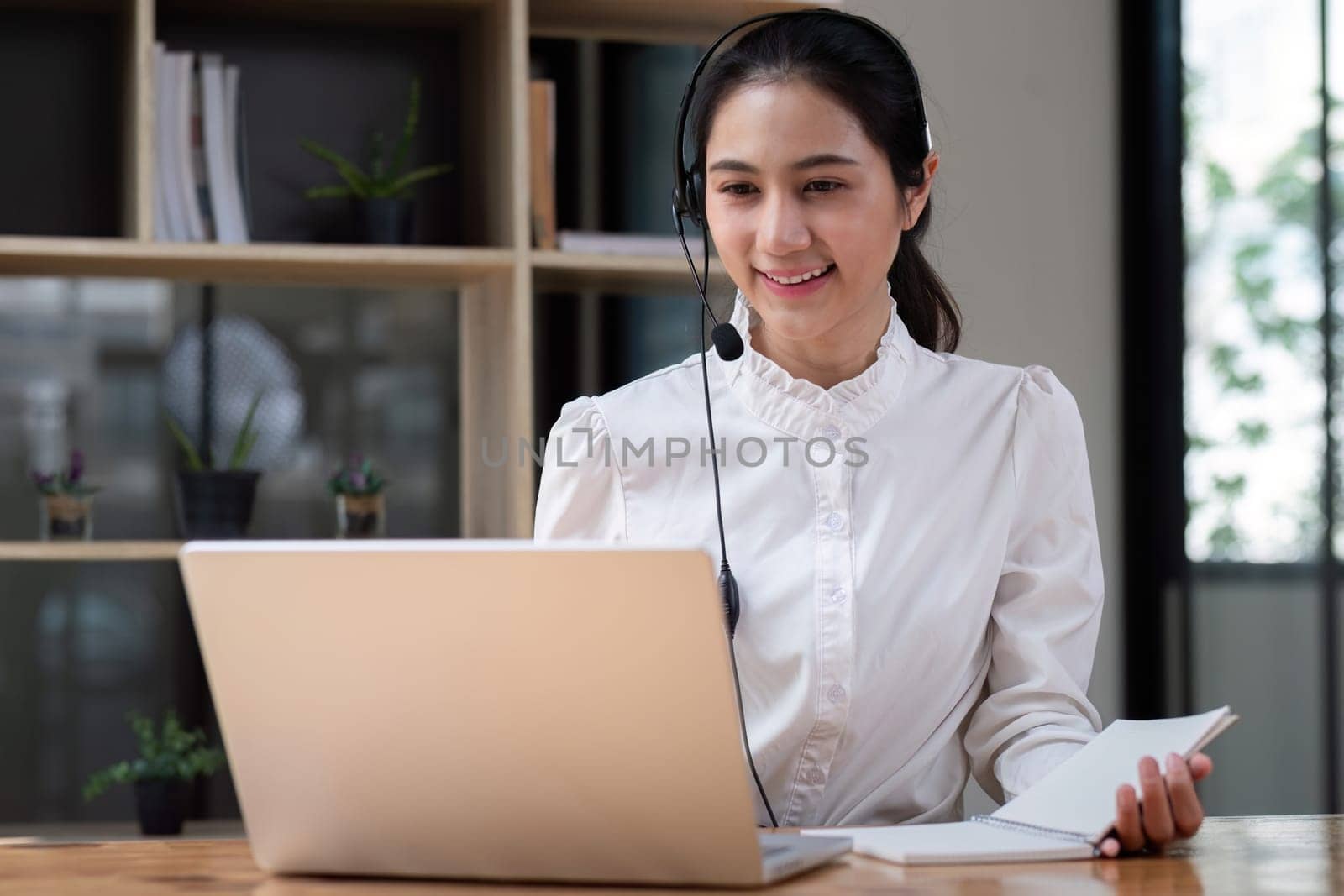 Call center agent with headset working on support hotline in office. Video conference.
