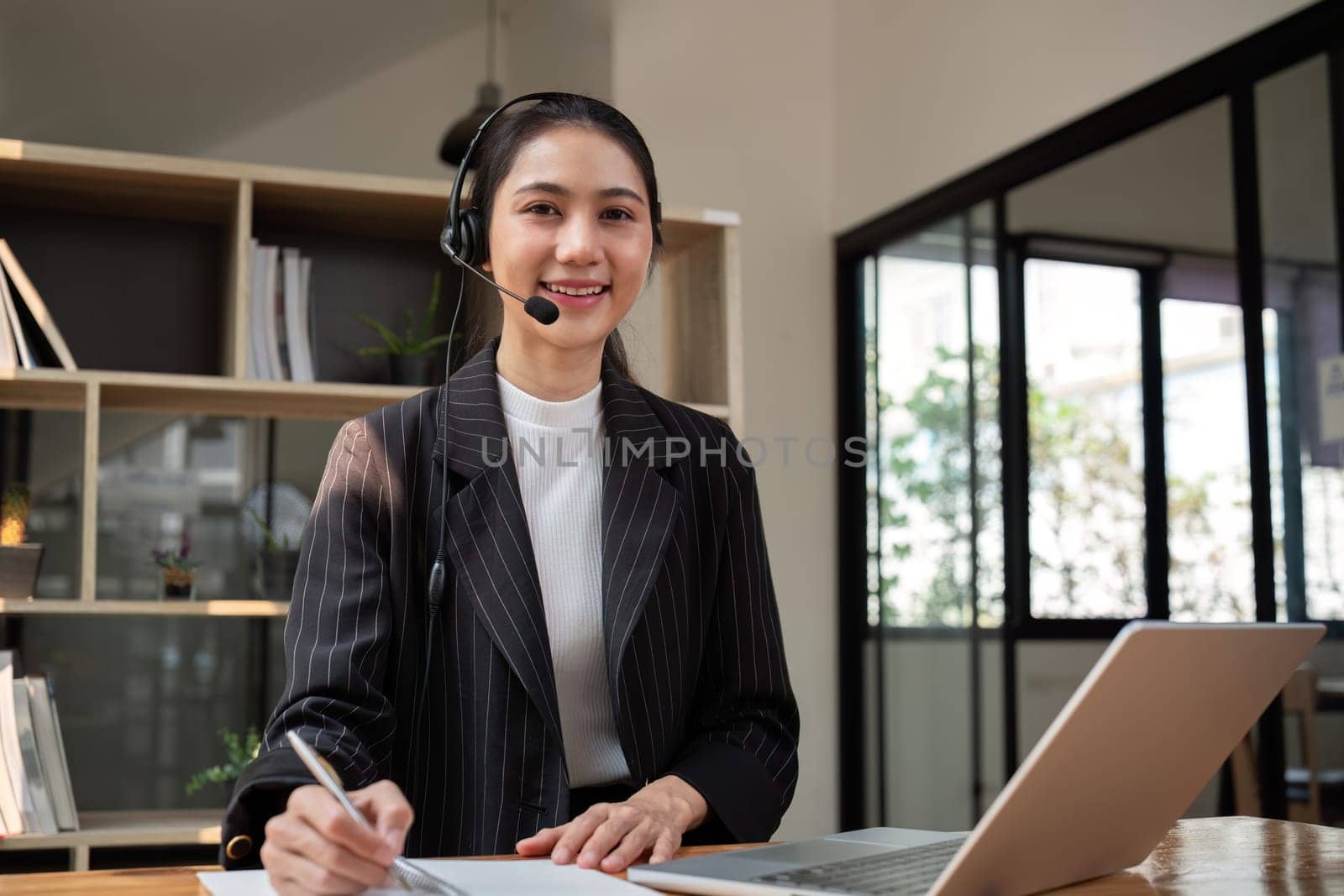 Call center agent with headset working on support hotline in office. Video conference.