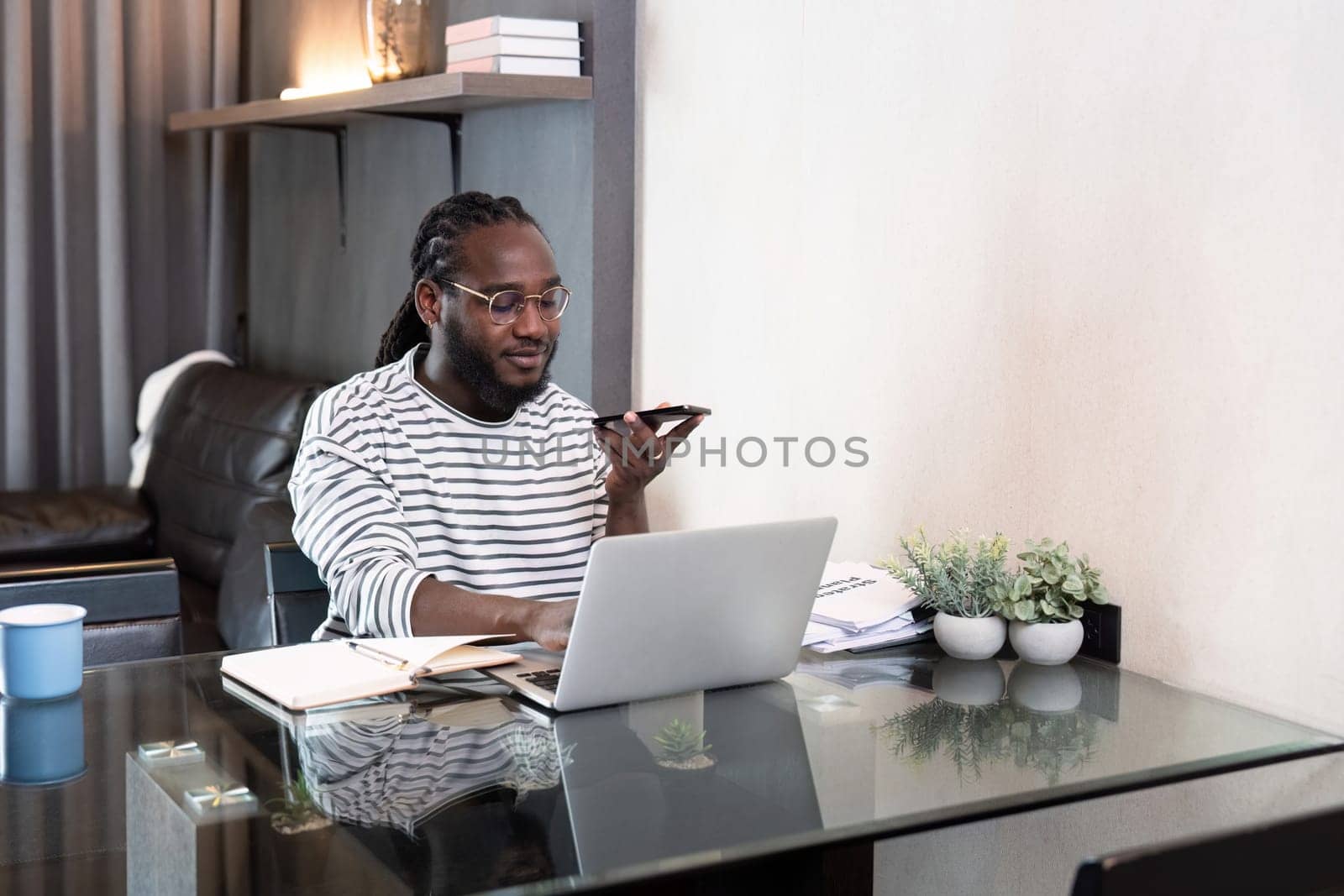 Professional man working remote from home with technology. African American male has a business meeting on an audio call phone by nateemee