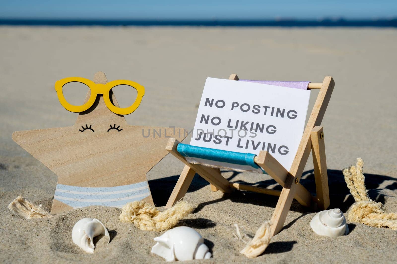 NO POSTING NO LIKING JUST LIVING text on paper greeting card on background of beach chair lounge starfish summer vacation decor. Concept of social media technology detox Sandy beach sun. Holiday postcard. Travel by anna_stasiia