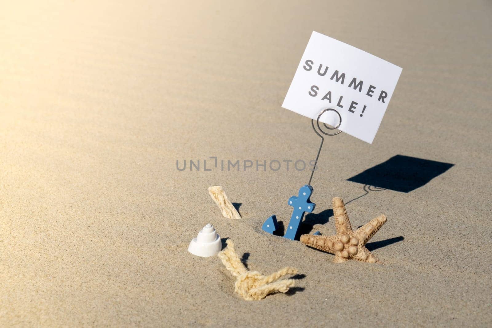 SUMMER SALE text on paper greeting card in anchor paper holder and starfish seashell summer vacation decor. Sandy beach sun coast. Promotion advertisement Holiday concept postcard. Getting away Travel Business concept