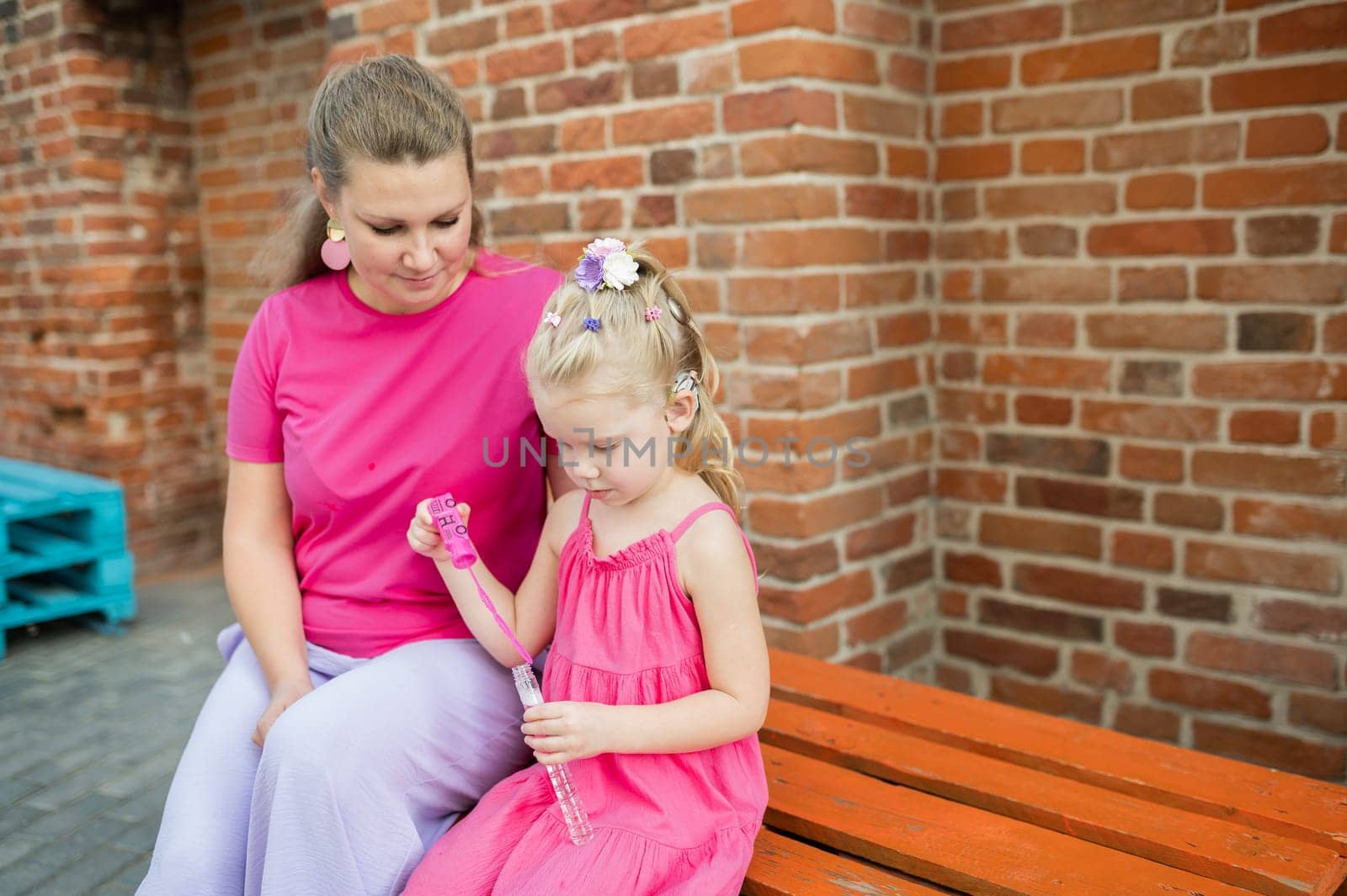 Deaf child with cochlear implant for hearing audio and aid for impairment having fun and laughs with mother outdoor in summer. Sound fitting device to help with communication listening and interaction.