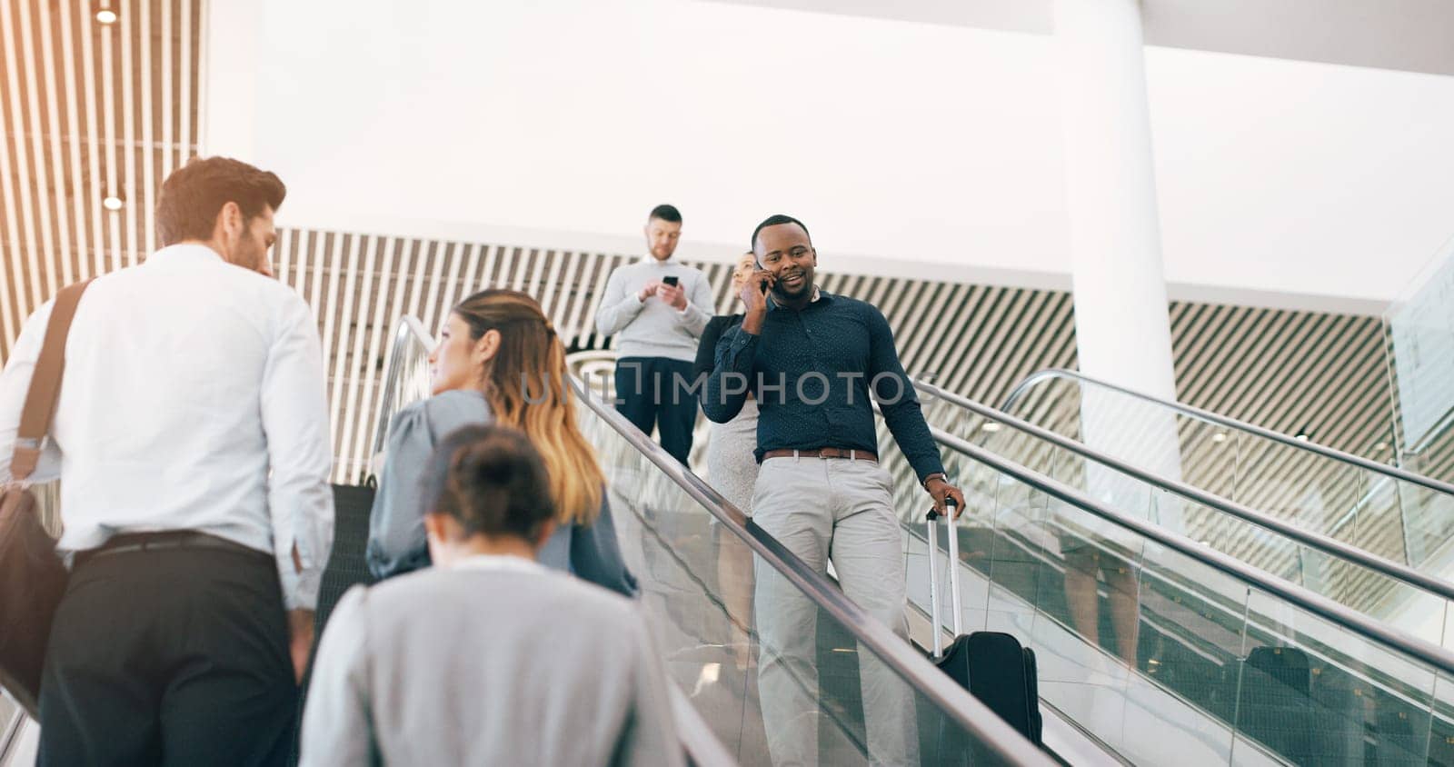 Businessman, escalator and talking with phone call for discussion or communication on work trip. Black man speaking on mobile smartphone in travel with luggage for immigration or new opportunity by YuriArcurs