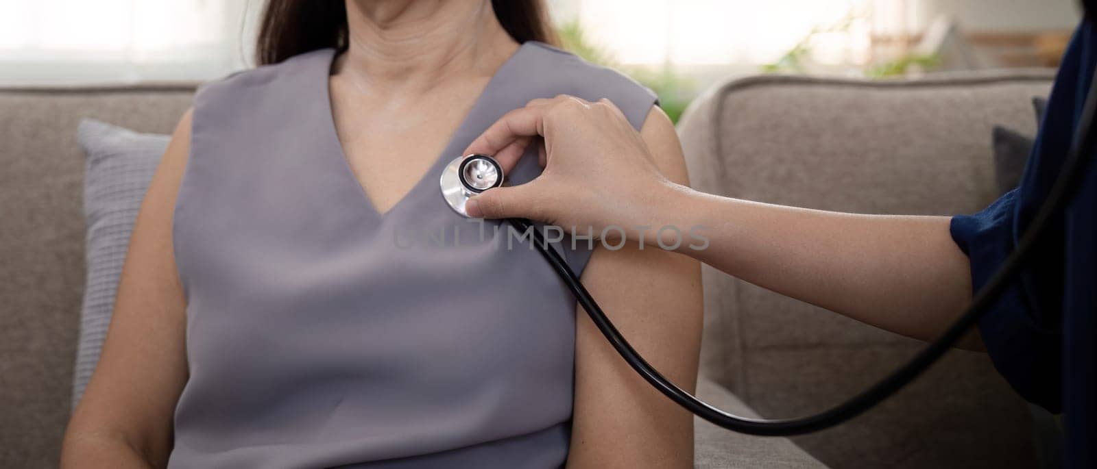 Elderly woman asian patient are check up health while a woman doctor or caregiver woman use a stethoscope to hear heart rate. elderly healthcare concept.