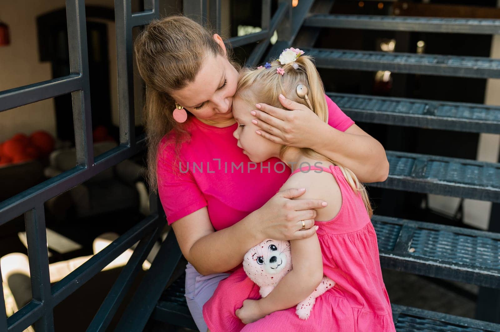 Mother holds and have fun her child with hearing aids and cochlear implants summer outdoor . Deaf and health concept. Diversity and inclusion. Copy space.