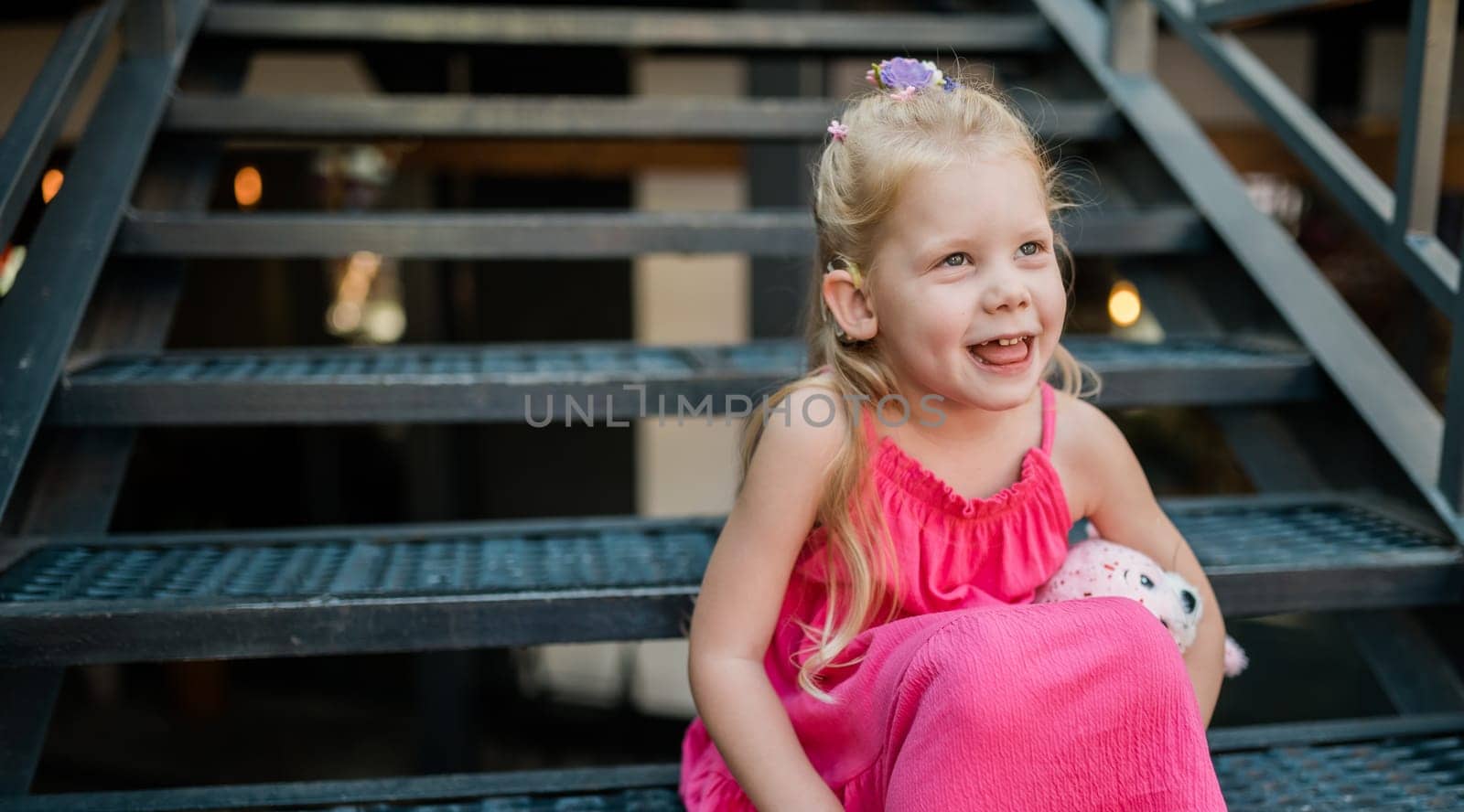 Child with hearing problem and cochlear implant dance in street, deaf kid began to hear. Hearing loss in childhood and treatment concept. Copy space and empty place for text.