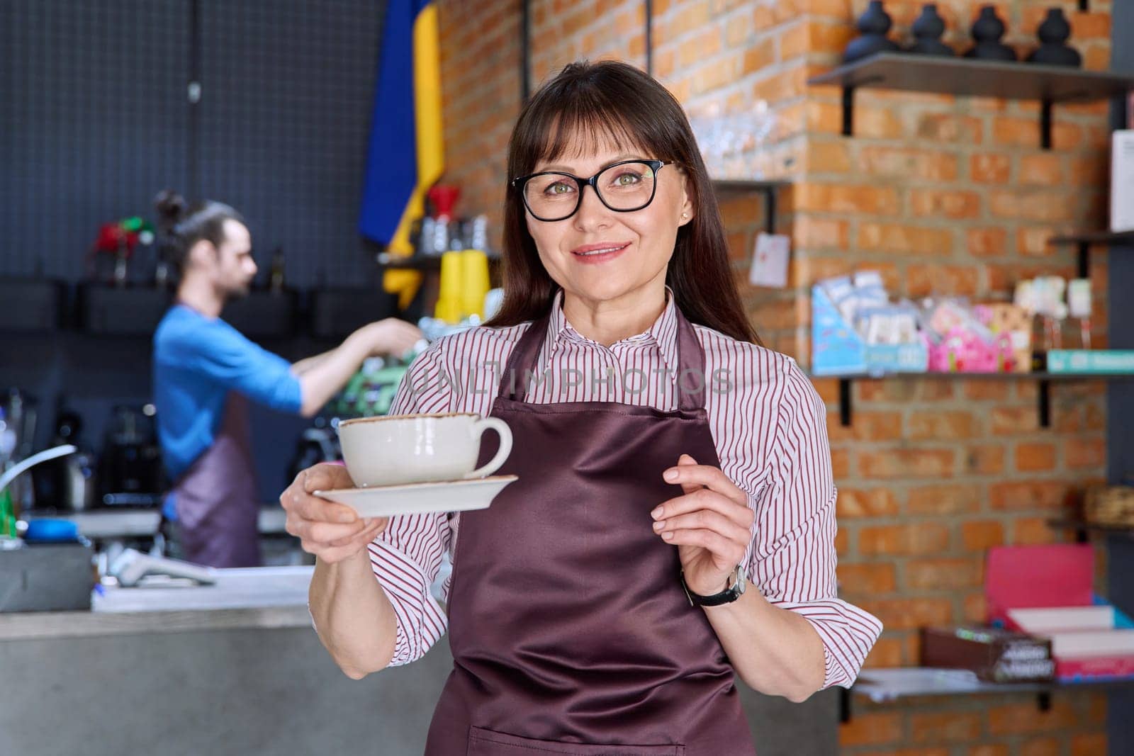 Woman in apron, food service coffee shop worker, small business owner with cup of coffee by VH-studio