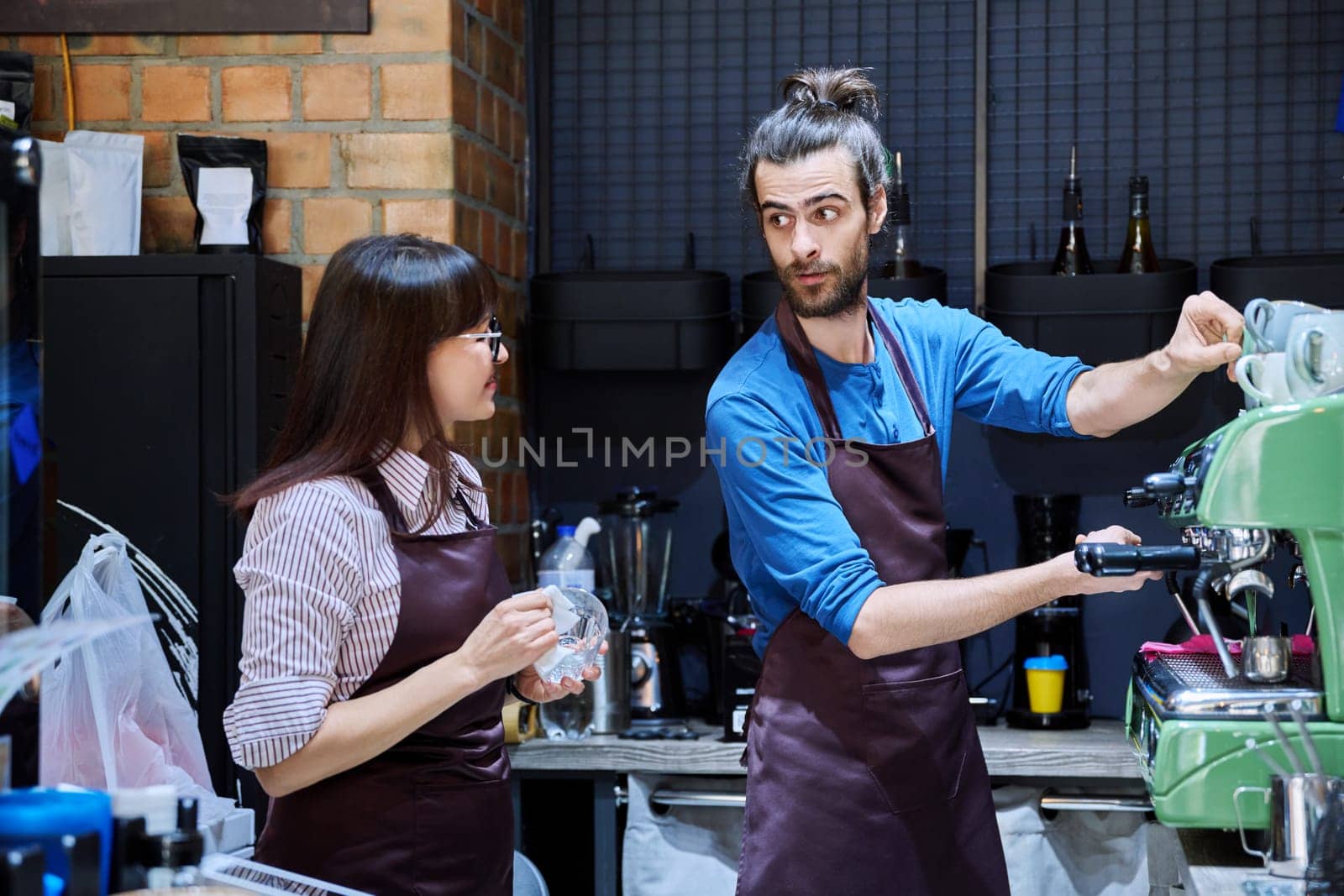 Teamwork, man and woman in aprons working together at bar counter in coffee shop cafe by VH-studio