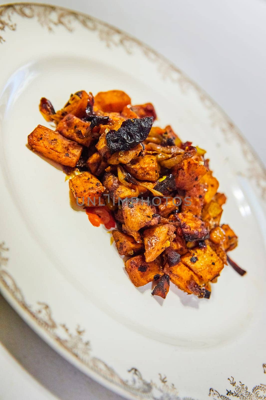 Deliciously caramelized root vegetables including sweet potatoes, served on a vintage white plate, captured in Fort Wayne, Indiana.