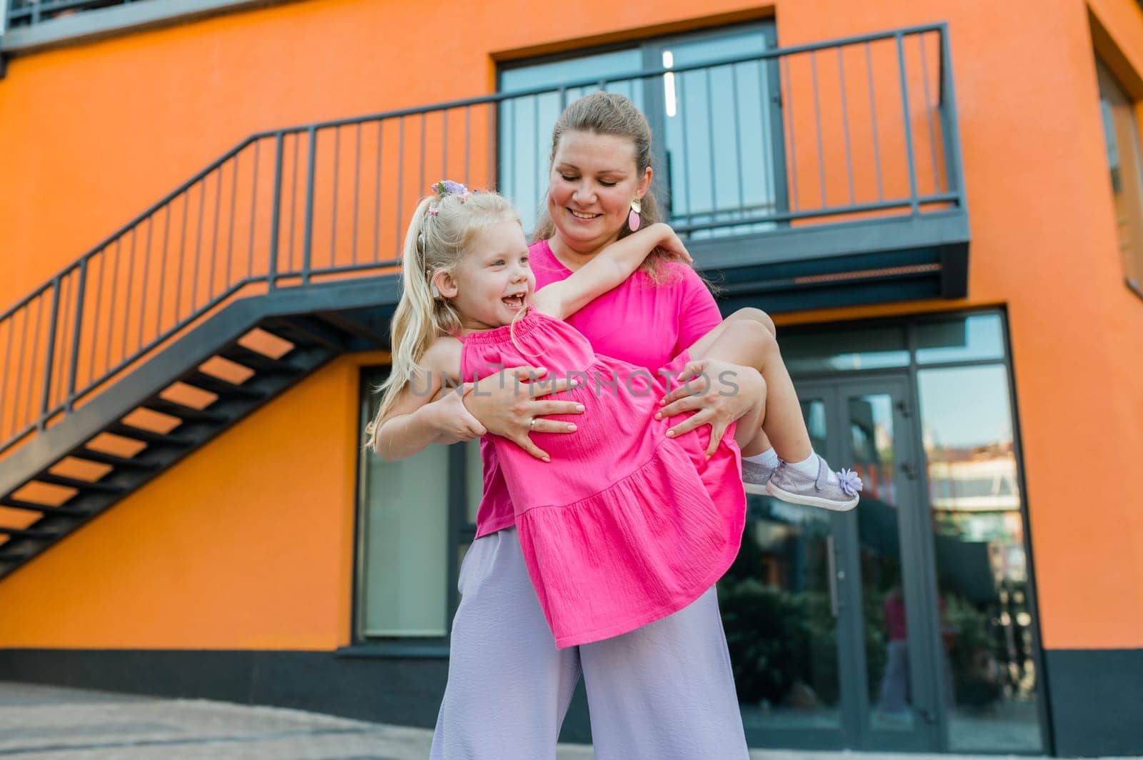 Deaf child with cochlear implant for hearing audio and aid for impairment having fun and laughs with mother outdoor in summer. Sound fitting device to help with communication listening and interaction.