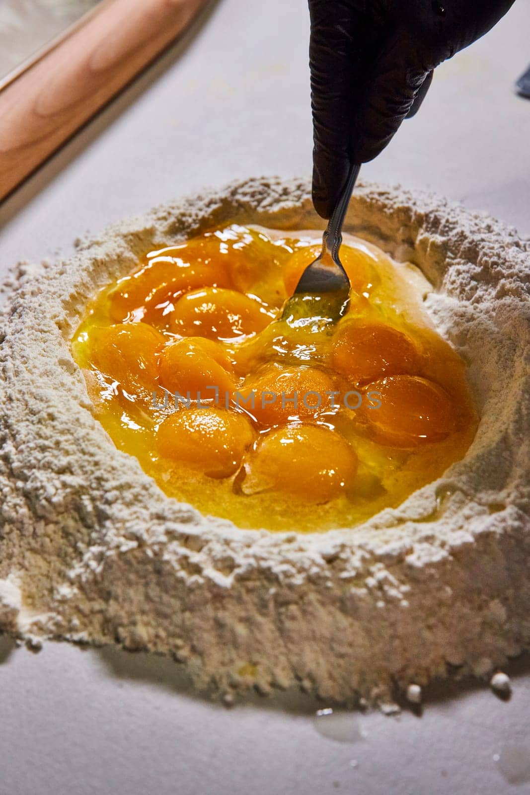 Culinary artistry in action in Fort Wayne, Indiana, demonstrating the hands-on process of mixing eggs and flour to make fresh, homemade pasta.