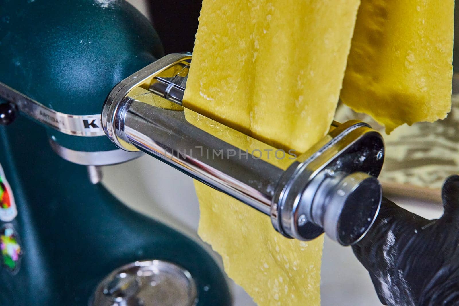 Freshly made homemade pasta passing through a kitchen mixer attachment, showcasing culinary arts in a Fort Wayne, Indiana home