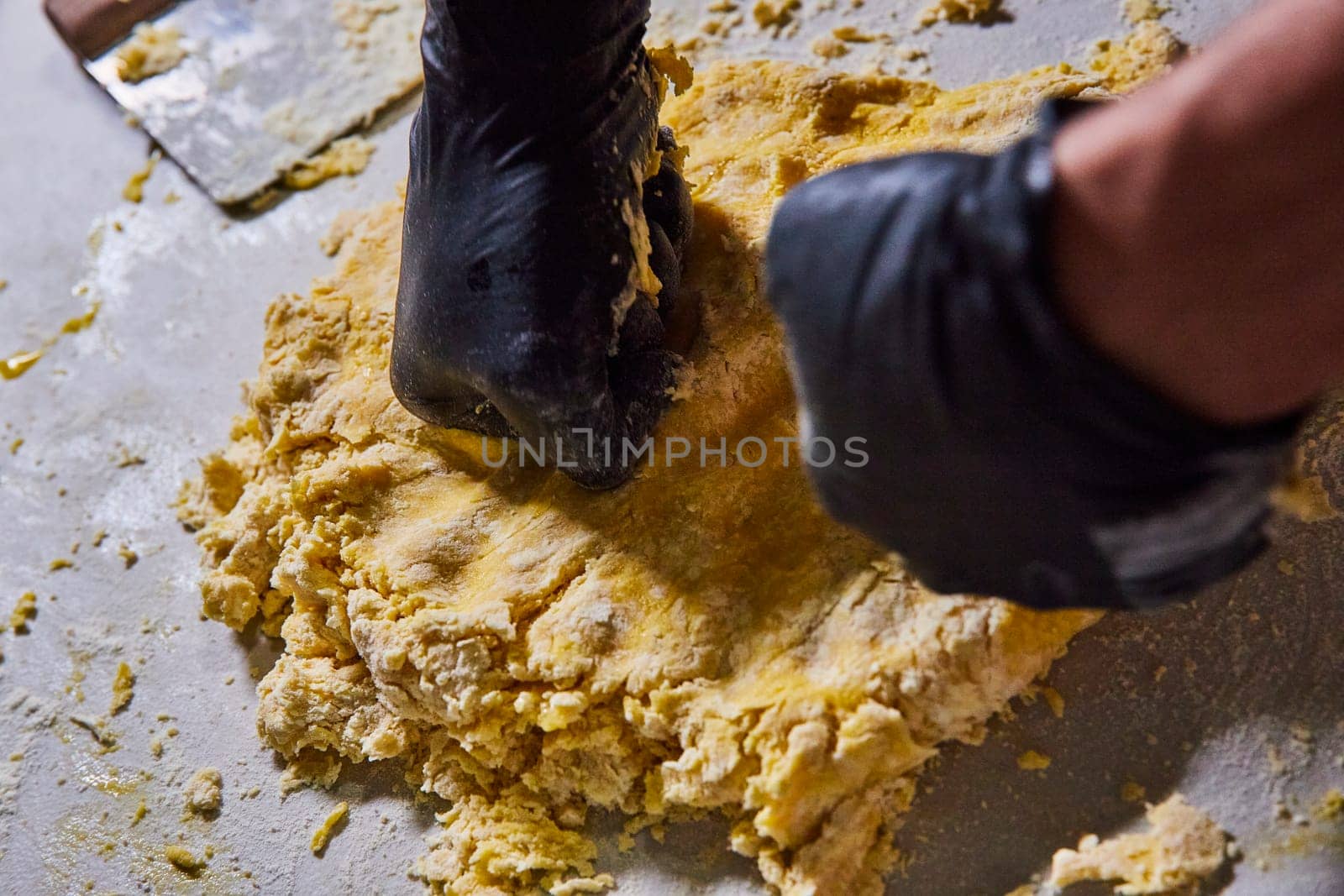 Artisan baker kneads fresh pasta dough in a professional kitchen, Fort Wayne, Indiana, showcasing culinary expertise and food safety.